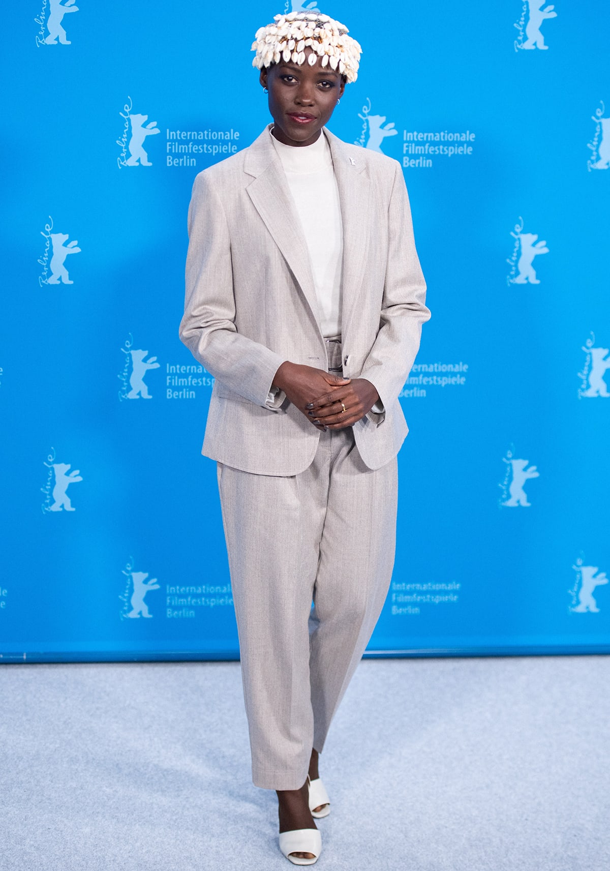 Lupita Nyong'o looks sharp in a beige suit with a white mock-neck tee and matching peep-toe mules at the 74th Berlin International Film Festival photocall on February 15, 2024