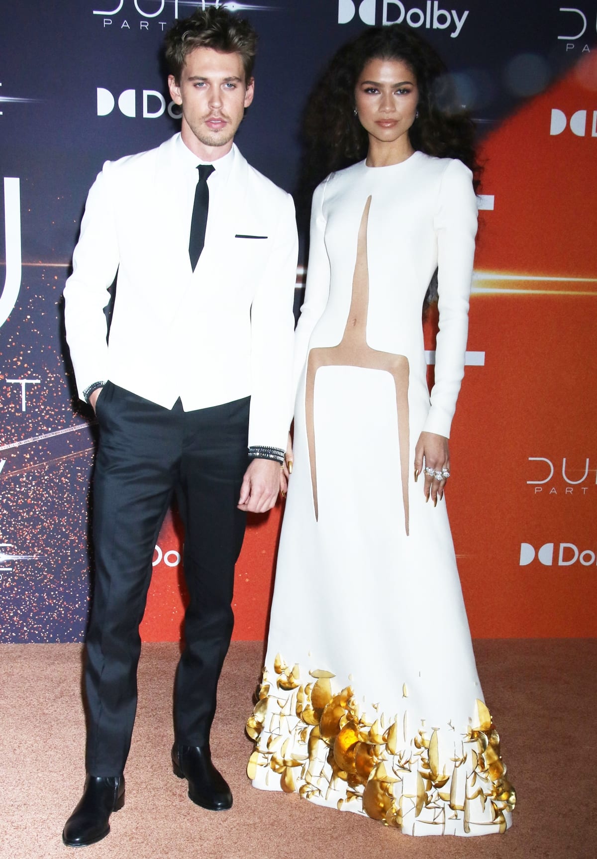 At the 'Dune: Part Two' premiere on February 25, 2024, in New York City, Austin Butler showcases a modern twist on classic style with an ivory Haider Ackermann tuxedo jacket, black trousers, and a crystal-studded cuff white shirt, standing alongside Zendaya