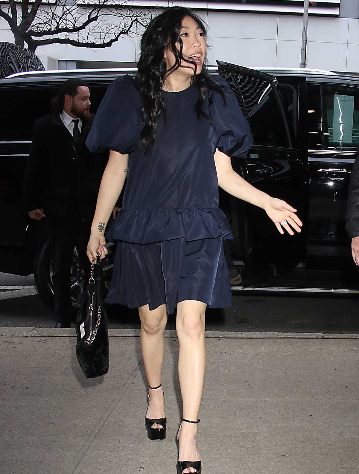 Awkwafina arrives at the Drew Barrymore Show studios in a navy-blue mini dress with puff sleeves and a peplum skirt on March 7, 2024