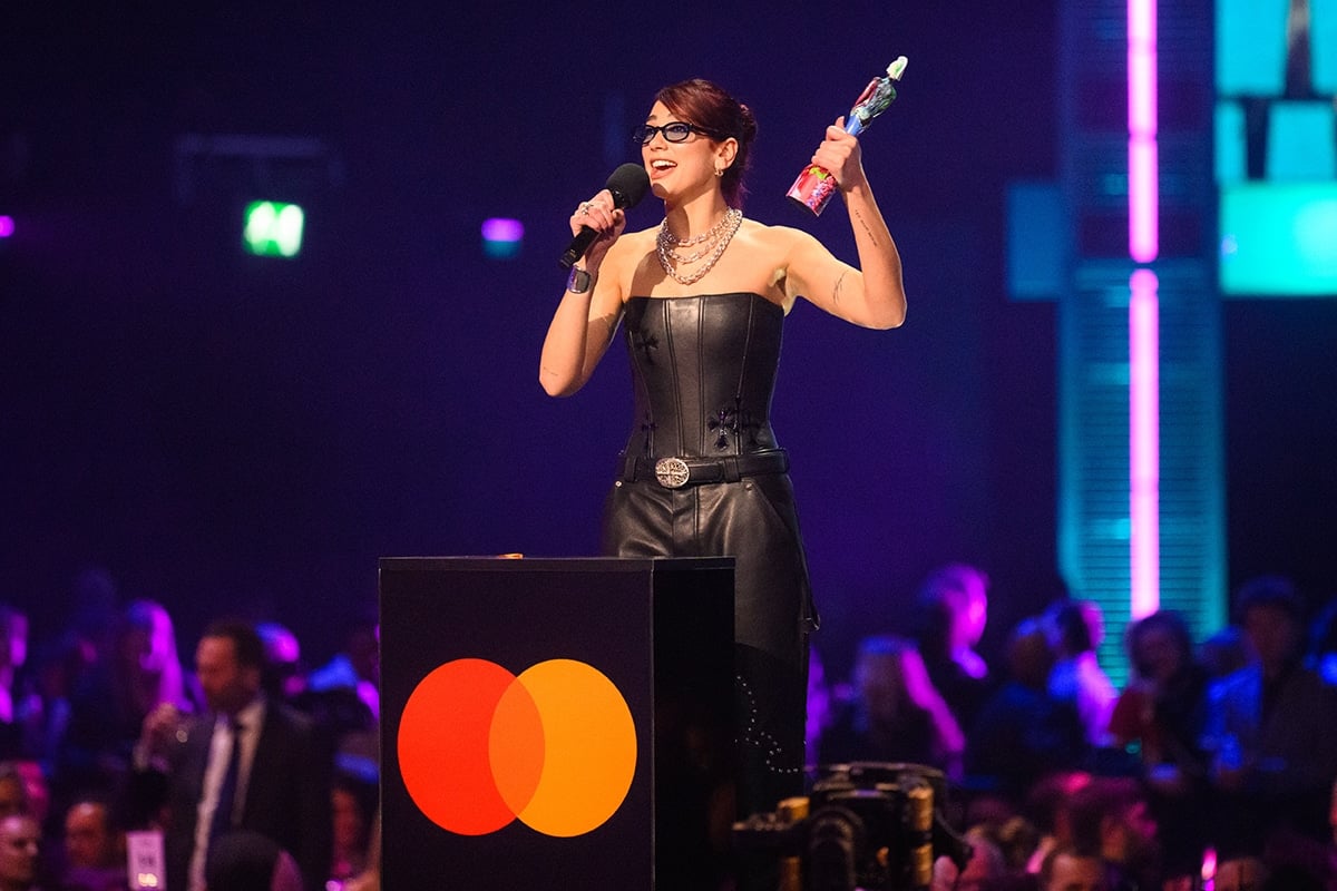 Dua Lipa collects her Brit Awards trophy in a strapless black leather corset top and belted leather pants by Chrome Hearts