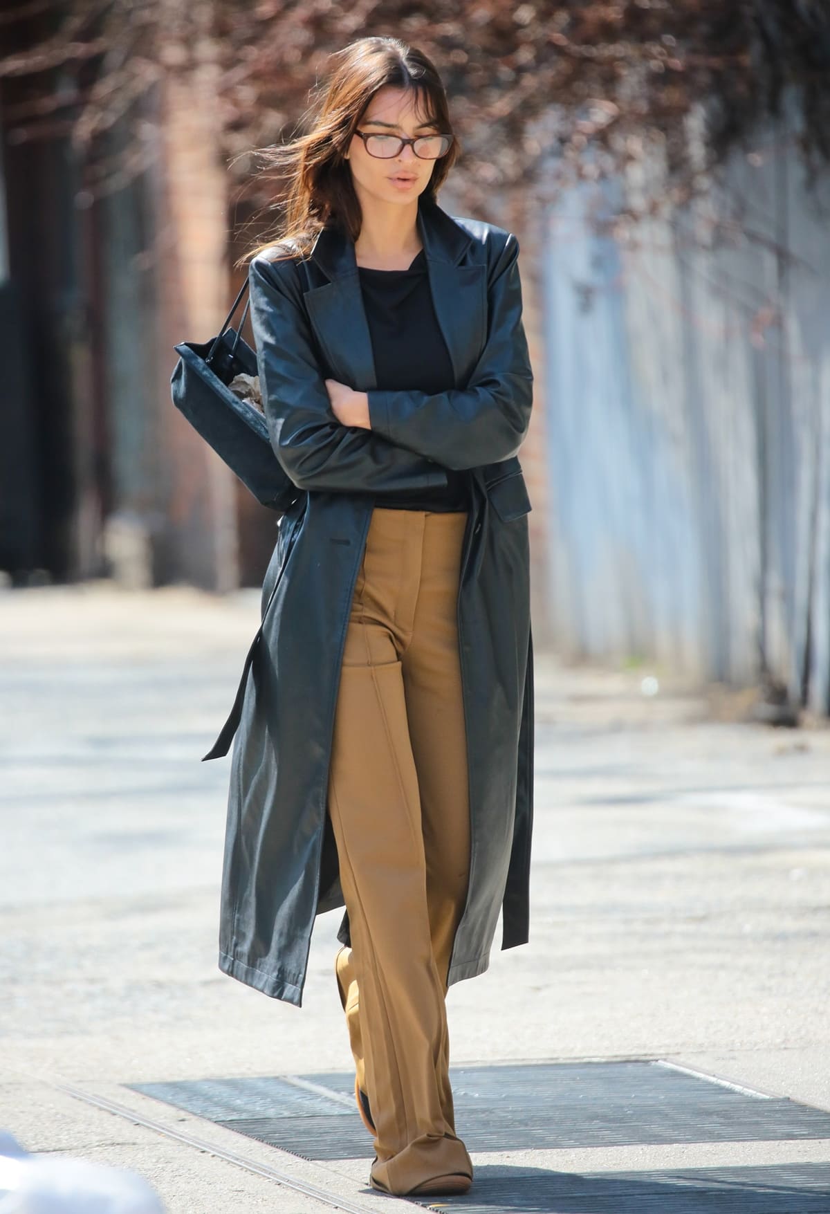 Emily Ratajkowski exudes effortless chic in a soft black boat neck top by Intimissimi and a classic leather coat, redefining casual sophistication on the streets of New York City