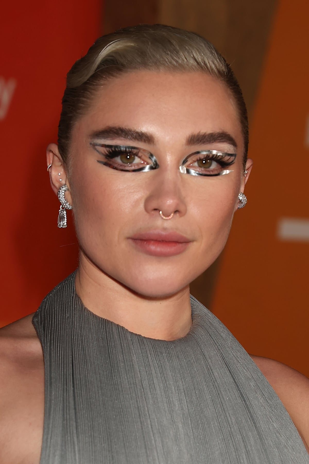 Florence Pugh captivates with her dramatic makeup at the 'Dune: Part Two' premiere, featuring graphic silver metallic eye makeup and bold brows, creating an otherworldly elegance that perfectly complements her Valentino gown