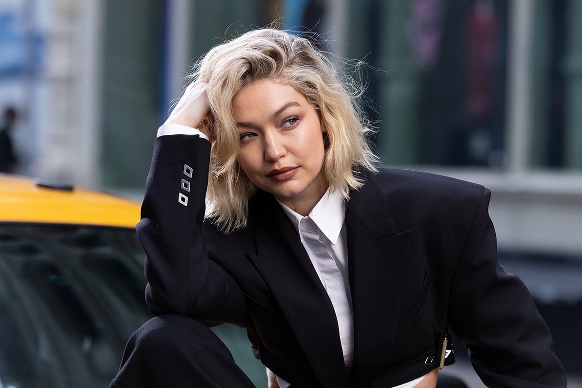 Gigi Hadid completes her edgy look with a messy bob and radiant makeup with smokey eyeshadow, peachy blush, and mauve lipstick