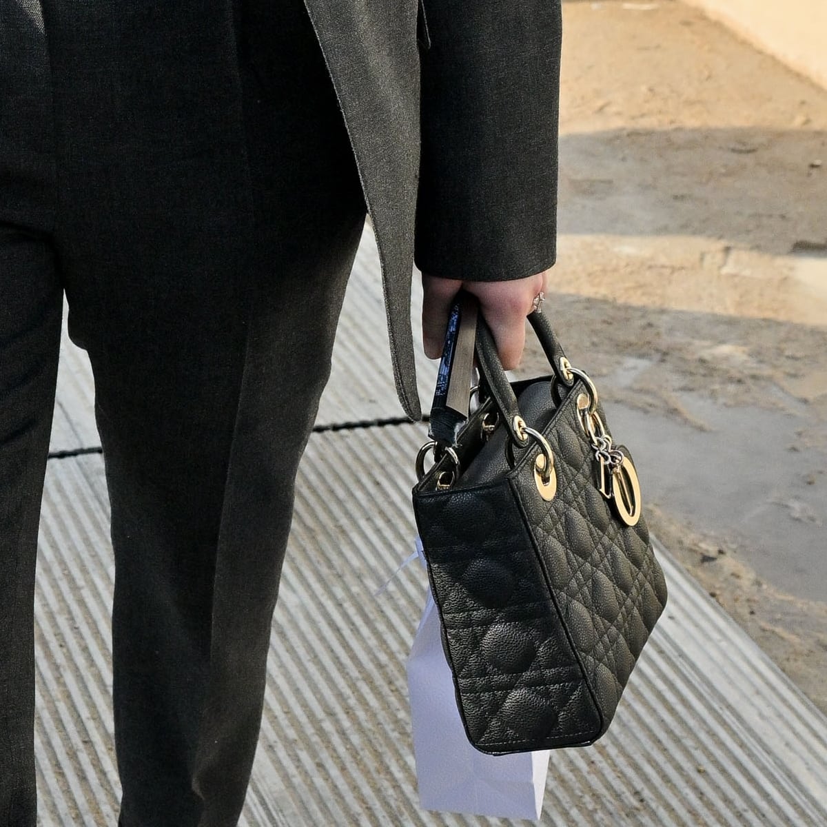 The classic Lady Dior top-handle bag in black leather with gold hardware adds a dash of edgy allure and timeless sophistication to Jennifer Lawrence's ensemble