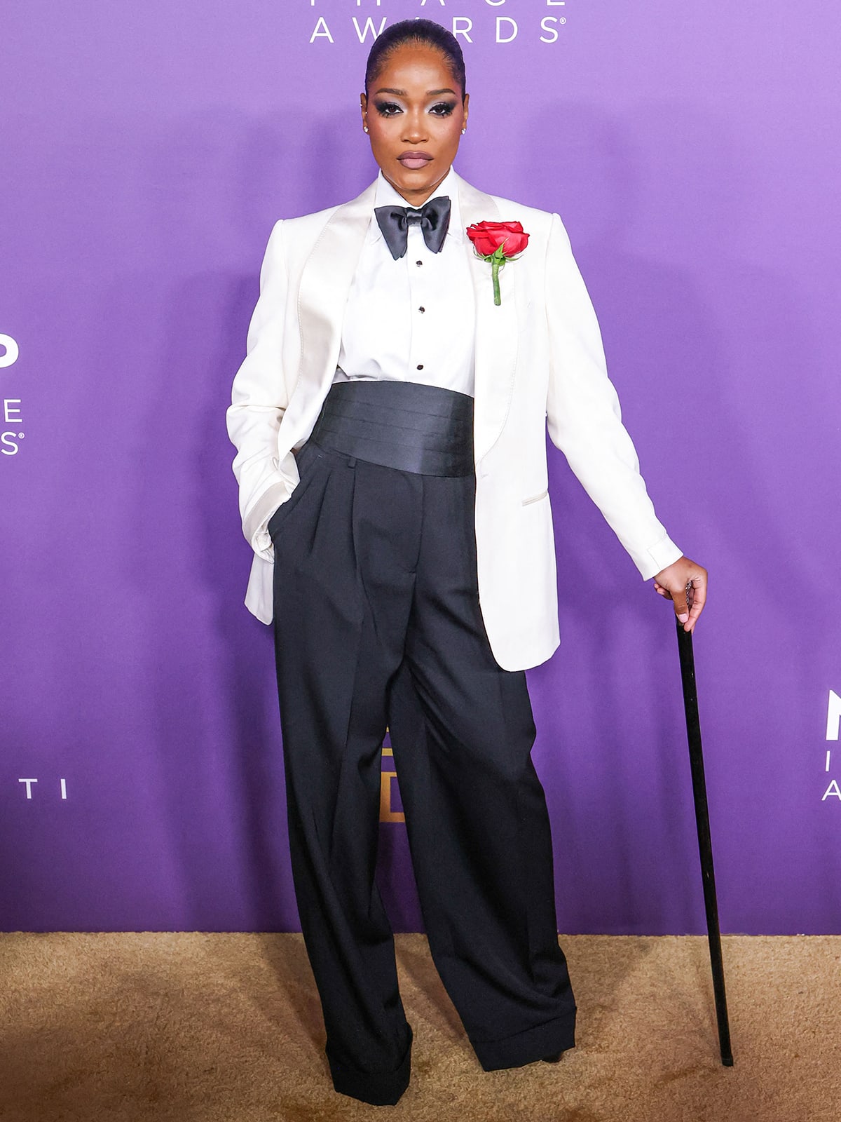 Keke Palmer looks sharp in a white tuxedo jacket with a white shirt and a black bowtie from Tom Ford teamed with a pair of wide-leg trousers and pumps by Dolce & Gabbana