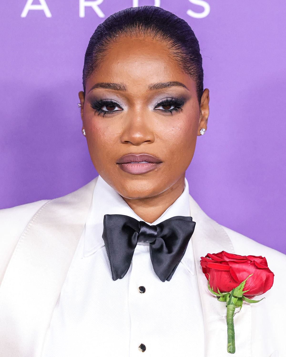 Keke Palmer glams up with smokey eyeshadow, dramatic lashes, mauve lipstick, and a sleek bun