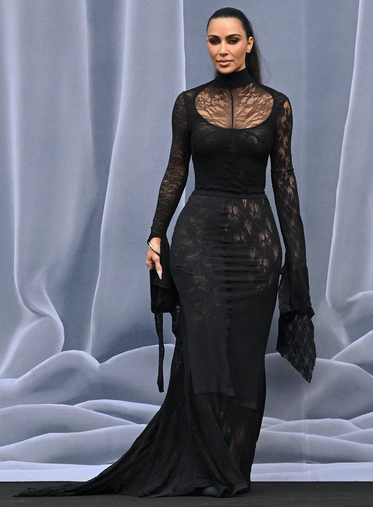 Captured at the moment of her arrival, Kim Kardashian exudes elegance and sophistication in a black lace Balenciaga gown during the Balenciaga womenswear Fall/Winter 2024-2025 collection show as part of Paris Fashion Week on March 3, 2024 in Paris, France