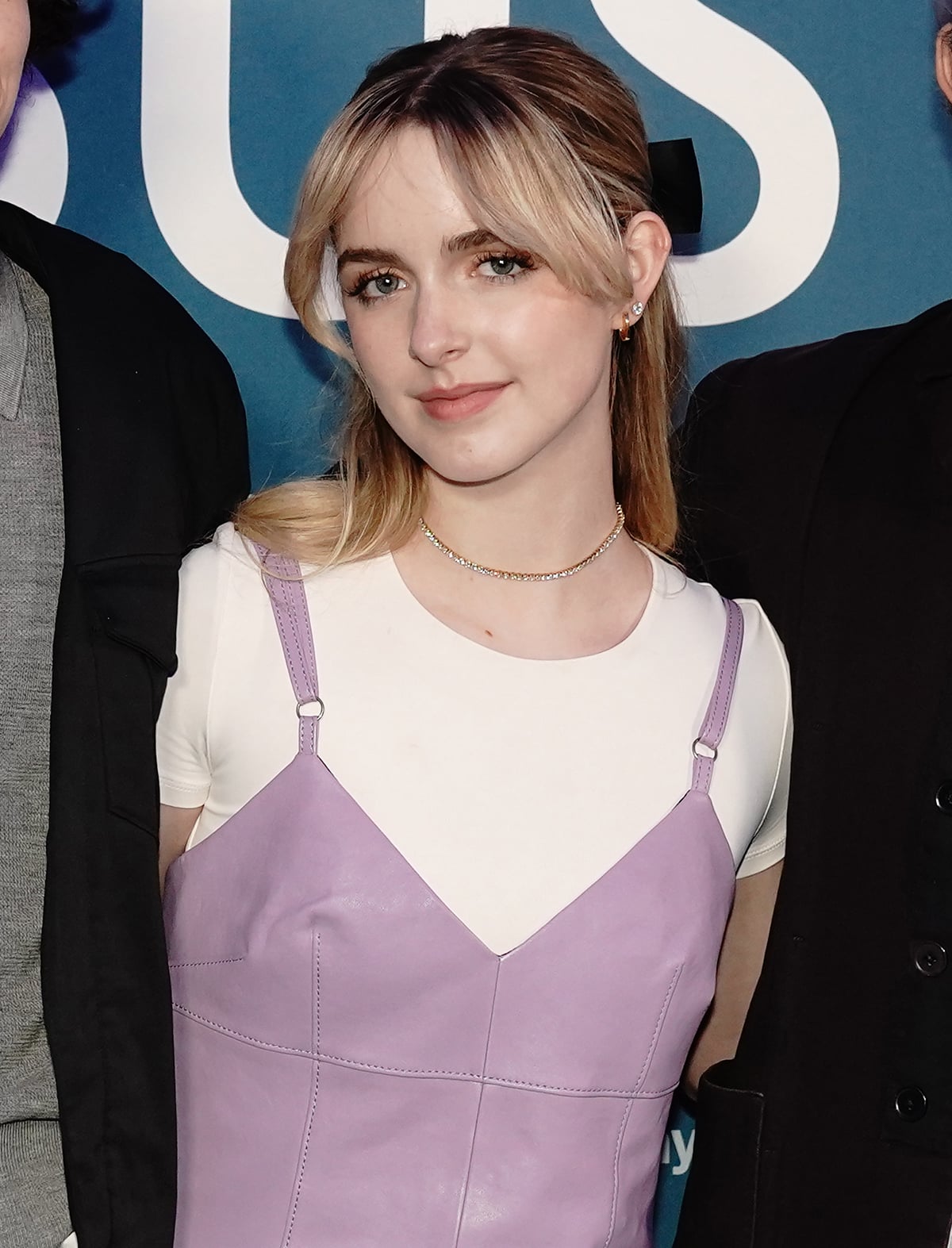 Mckenna Grace wears her blonde hair in a half-up ponytail with a black bow and highlights her youthful appearance with soft makeup