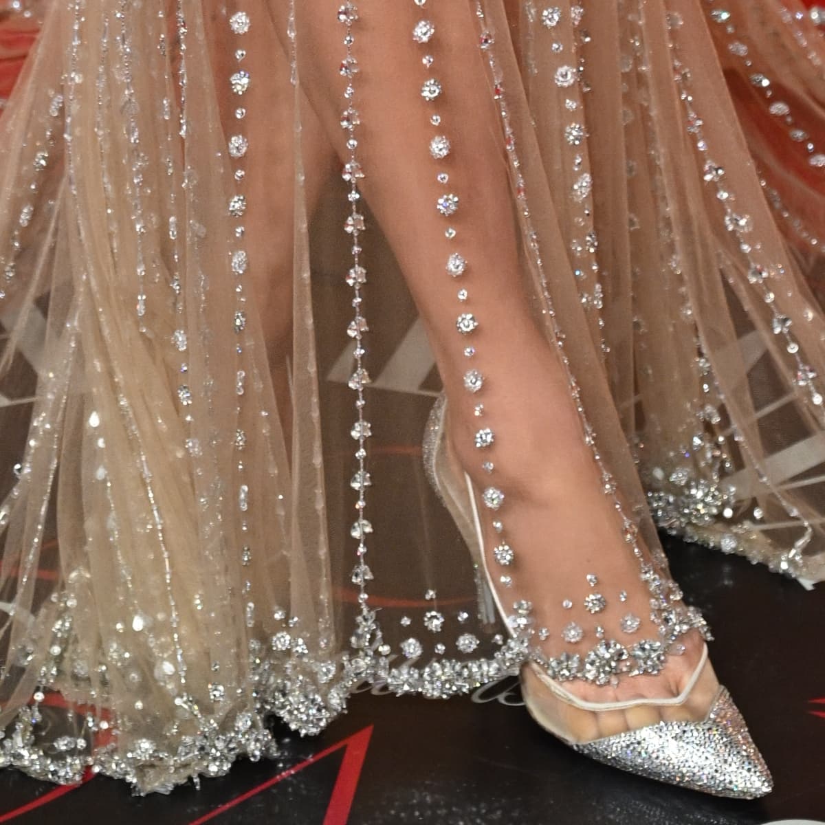 A close-up of Paris Hilton's feet adorned in sparkling Aquazzura Cara Mia pumps, the mirrored Swarovski crystals glistening, perfectly matching her glamorous attire