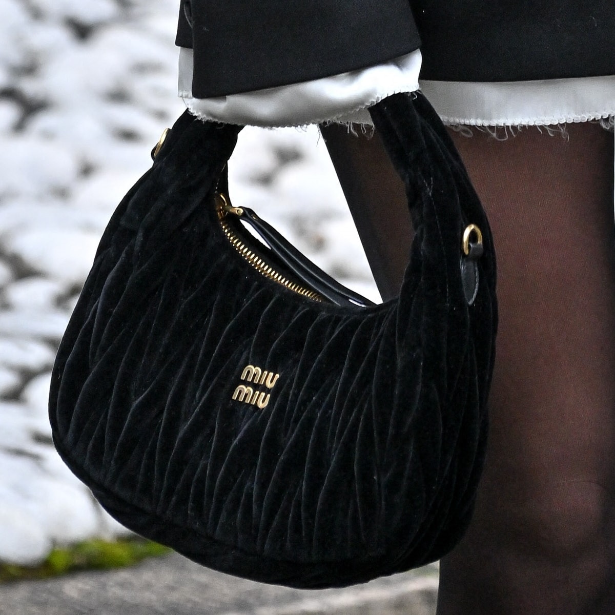 Sydney Sweeney complements her Paris Fashion Week ensemble with a touch of luxury, carrying a quilted Miu Miu Wander Matelassé black velvet hobo bag, a perfect blend of sophistication and style