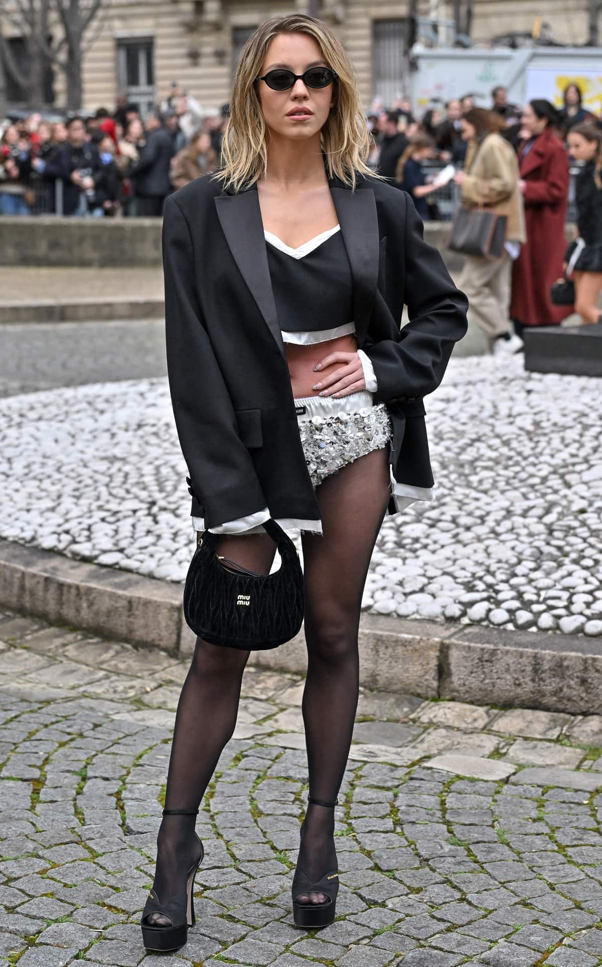 Sydney Sweeney radiates confidence at Paris Fashion Week, showcasing a daring no-pants look with Miu Miu's glittering silver briefs and sheer black tights