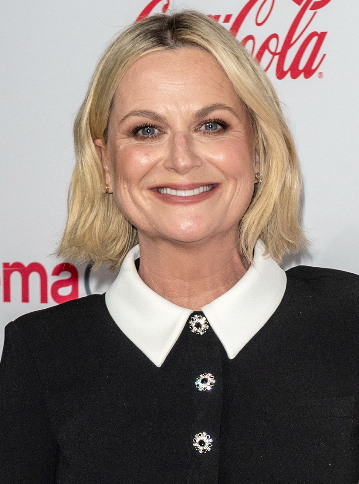Amy Poehler wears her blonde bob in soft waves and highlights her blue eyes with smudged, smokey eyeshadow