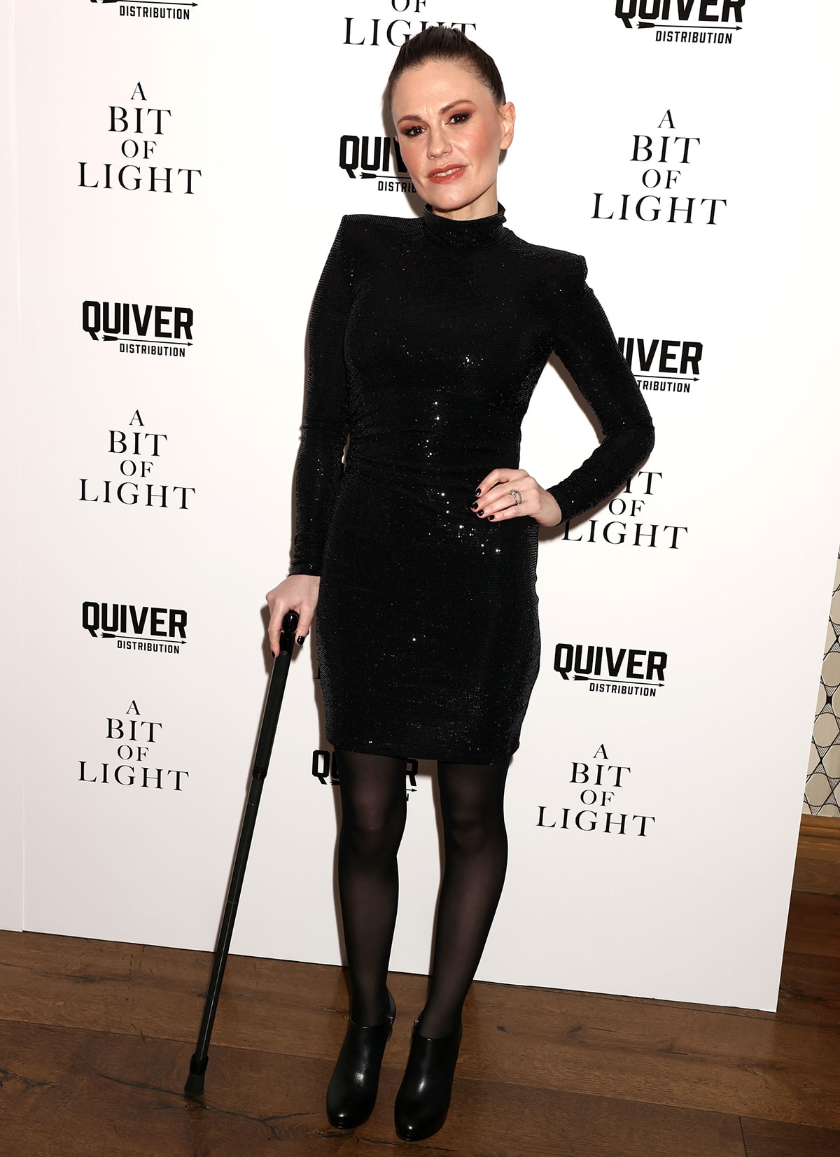 Anna Paquin wows in a sparkly Nookie little black dress cut from foil sequin fabric with a mock neck, long sleeves, and a thigh-skimming hem