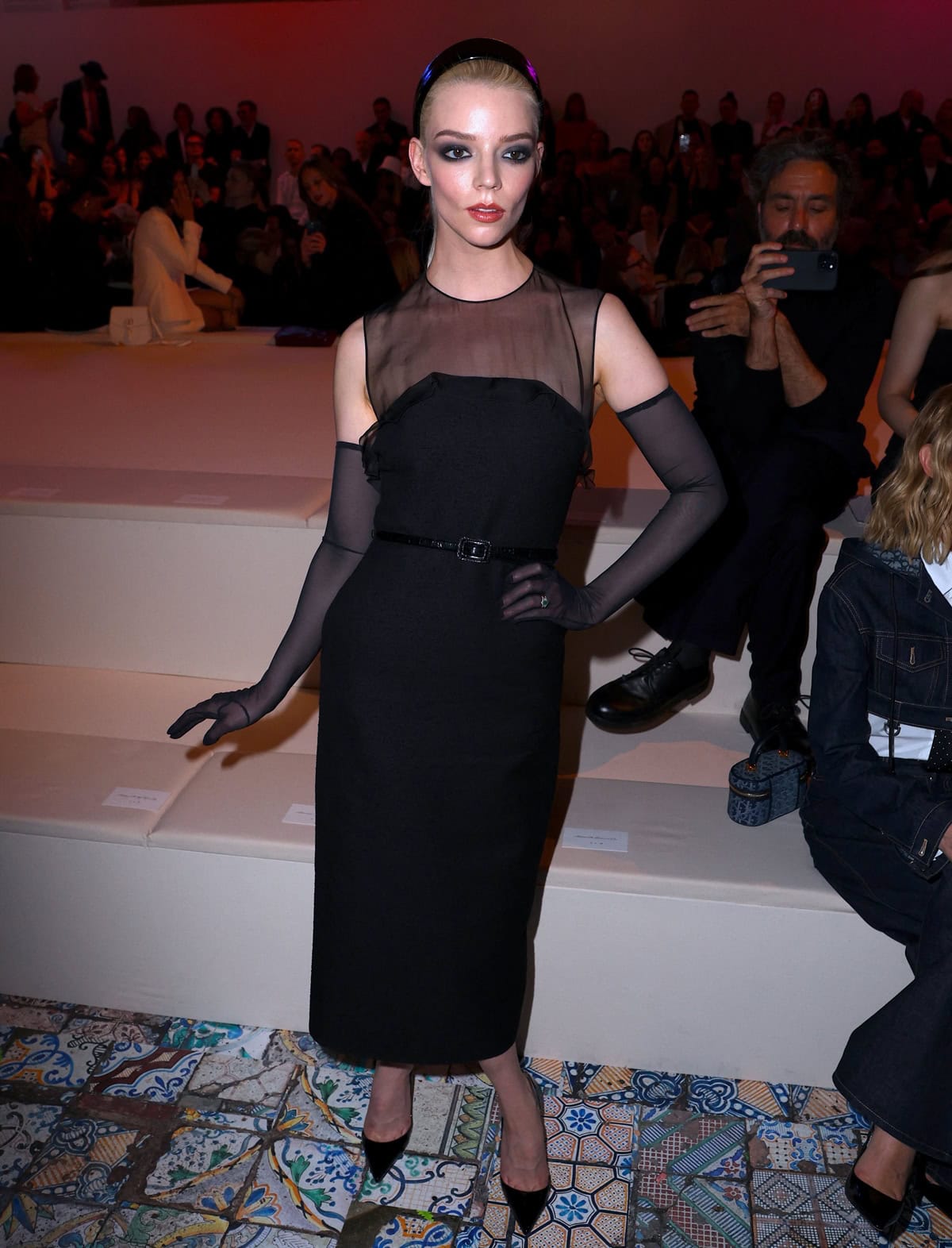 Anya Taylor-Joy attends Christian Dior's Pre-Fall 2024 runway show in a stunning black semi-sheer midi dress by Maria Grazia Chiuri, featuring a sleeveless silhouette and delicate frills at the strapless neckline, exemplifying timeless elegance at the Brooklyn Museum event