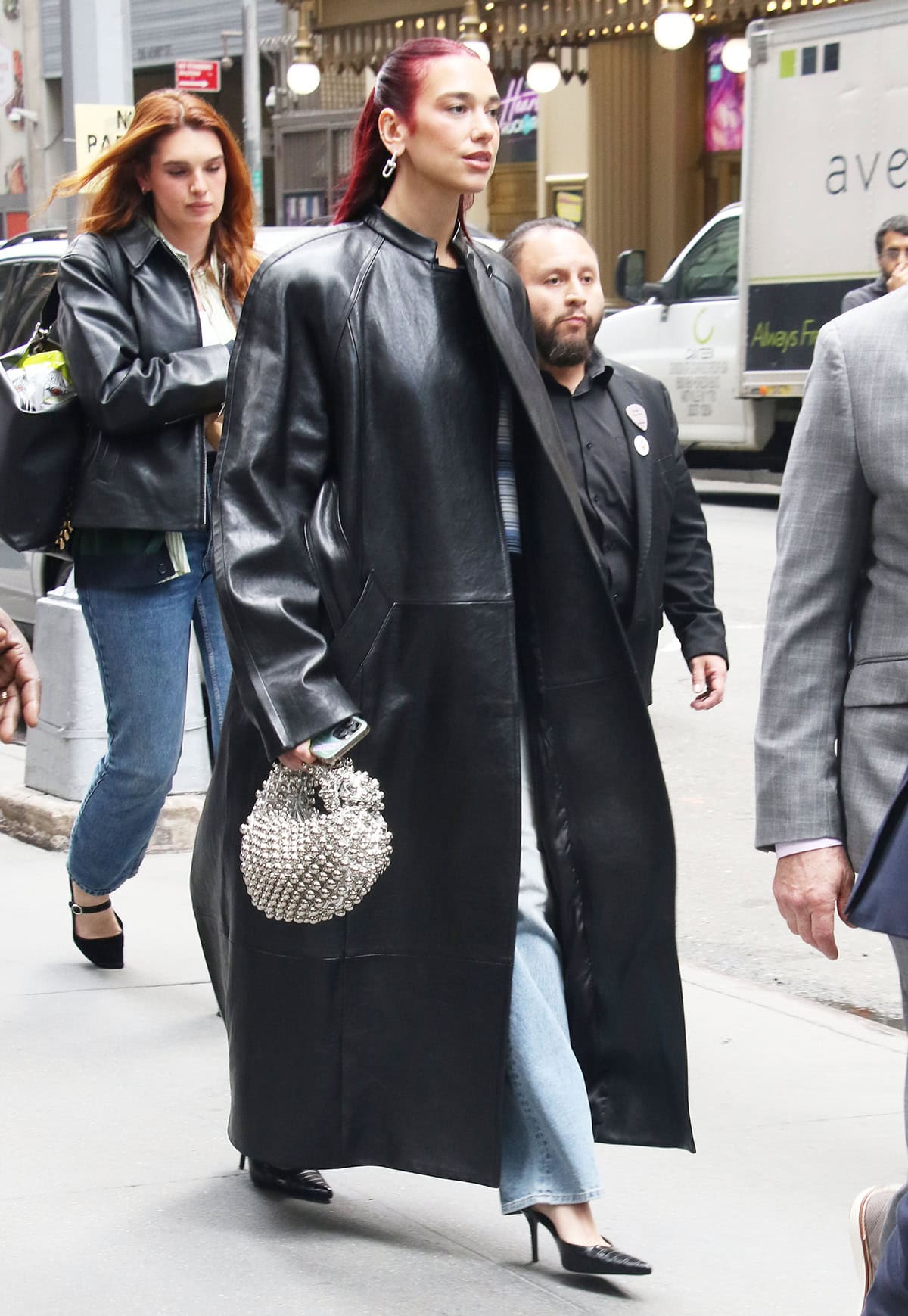 Dua Lipa promotes her upcoming third studio album, Radical Optimism, in a black leather Khaite trench coat and a blue striped Celine polo shirt at Hard Rock Cafe in New York City on April 24, 2024