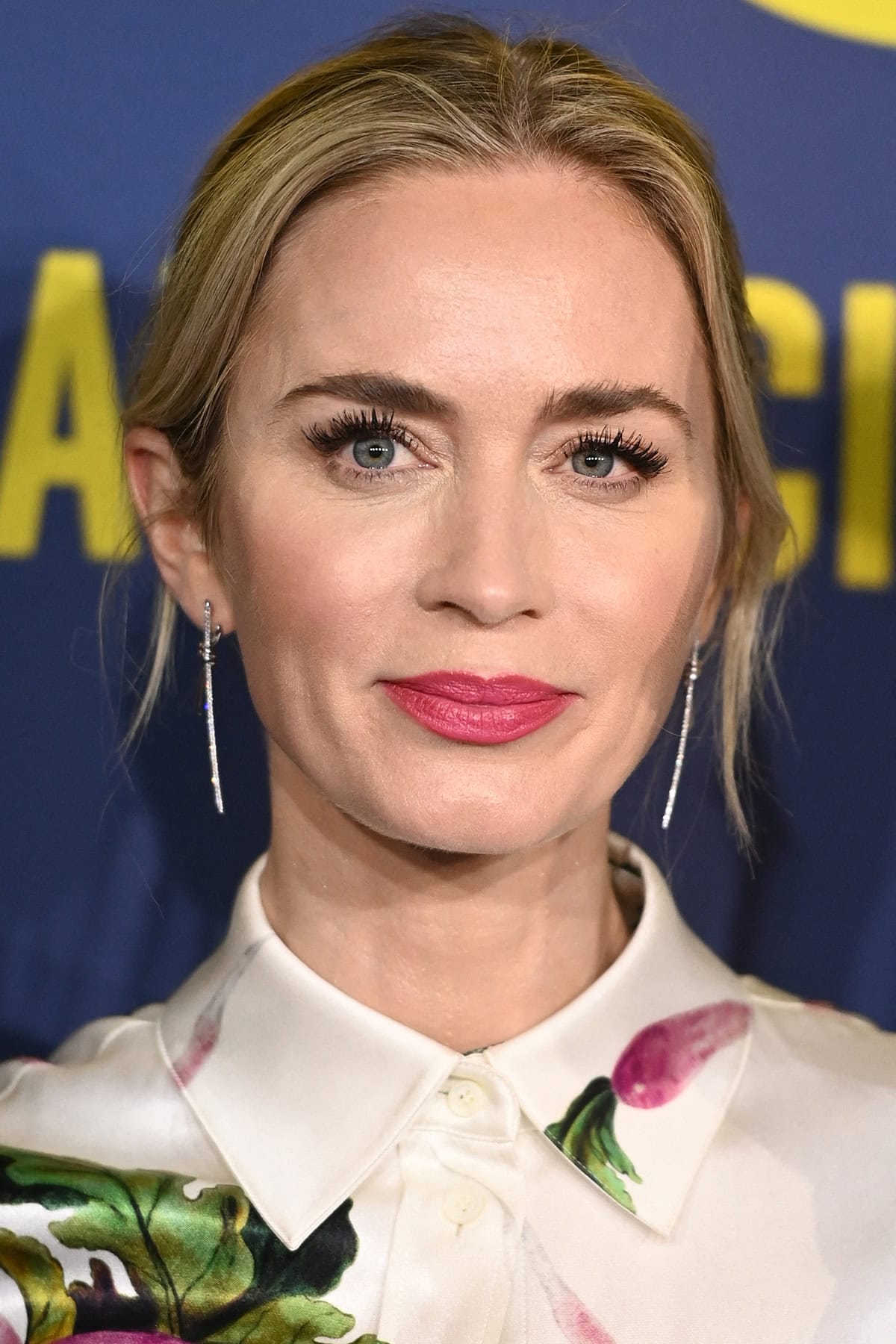 Emily Blunt wears a casual updo and coordinates her outfit with her glam by wearing fuchsia pink lipstick and blush