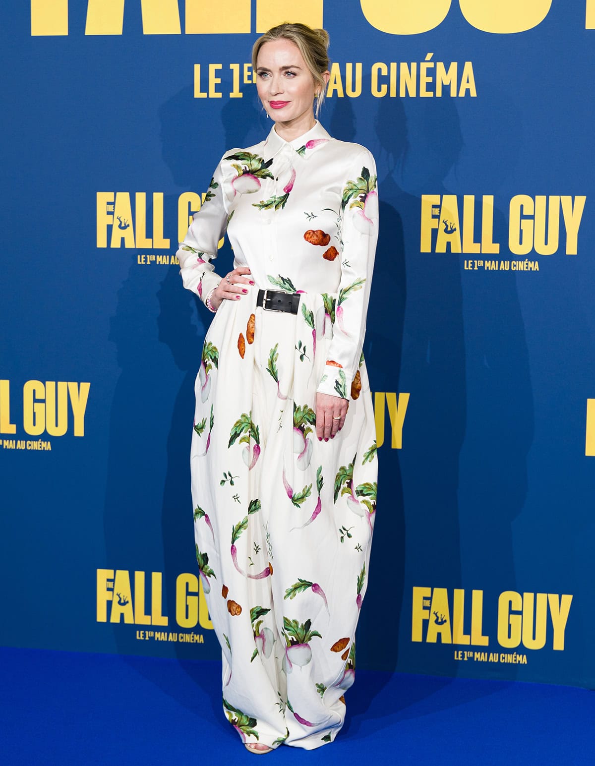 Emily Blunt's white vegetable-printed outfit features a collared, long-sleeved blouse and belted high-waist balloon trousers