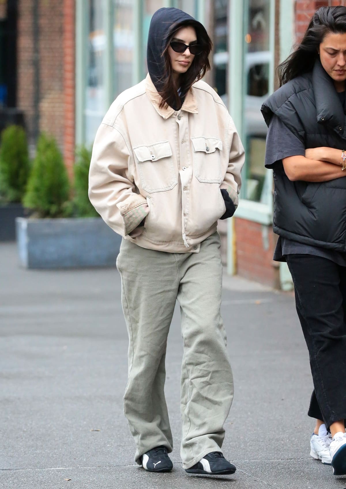 Emily Ratajkowski proves casual can be chic, pairing a black hoodie with a Yeezy denim jacket and Puma Speedcat sneakers