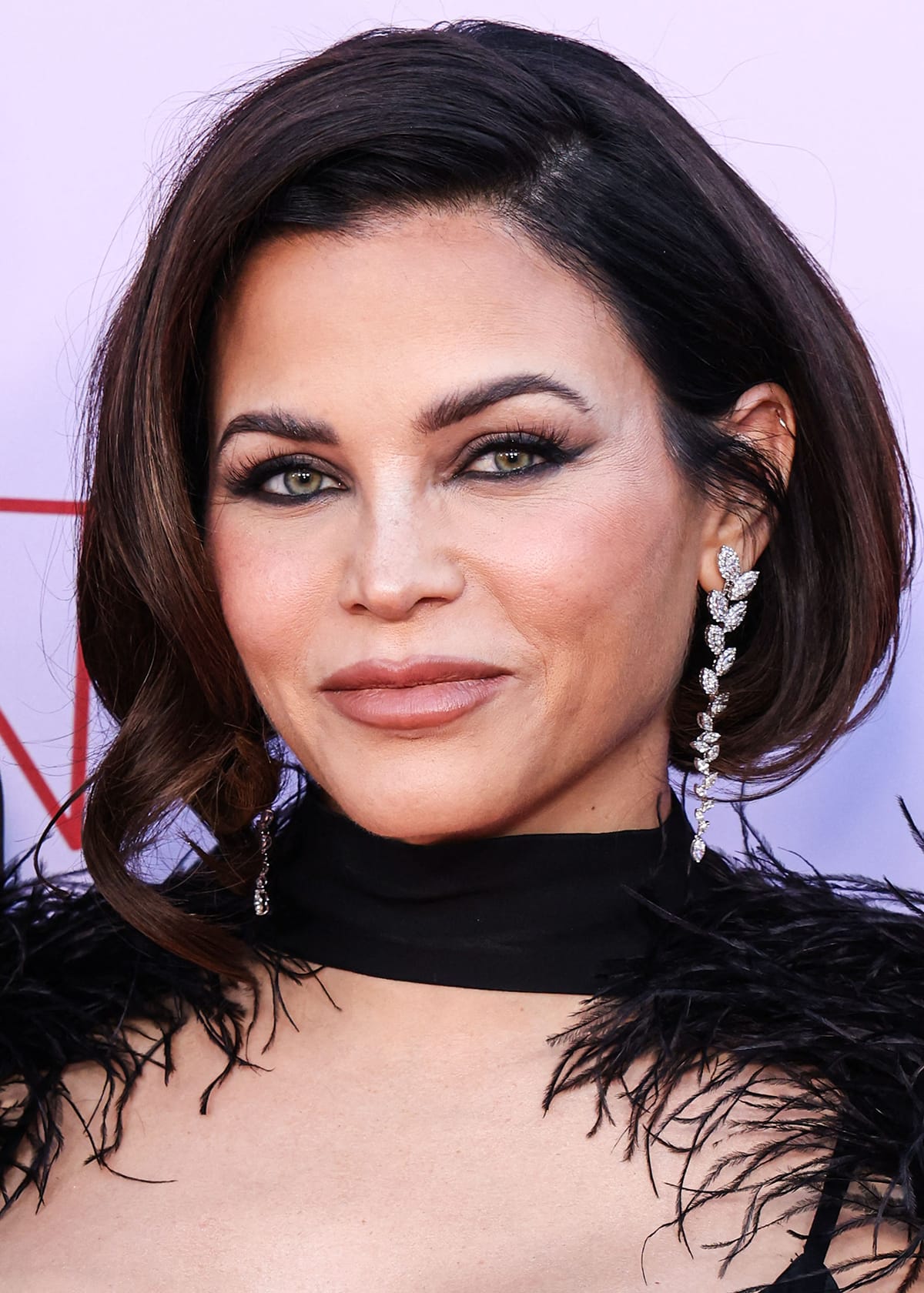 Jenna Dewan debuts a shorter bob hairstyle and completes the gothic-glam theme of her black feathered look with black smokey eyeshadow, kohl-rimmed eyes, and nude pink lipstick