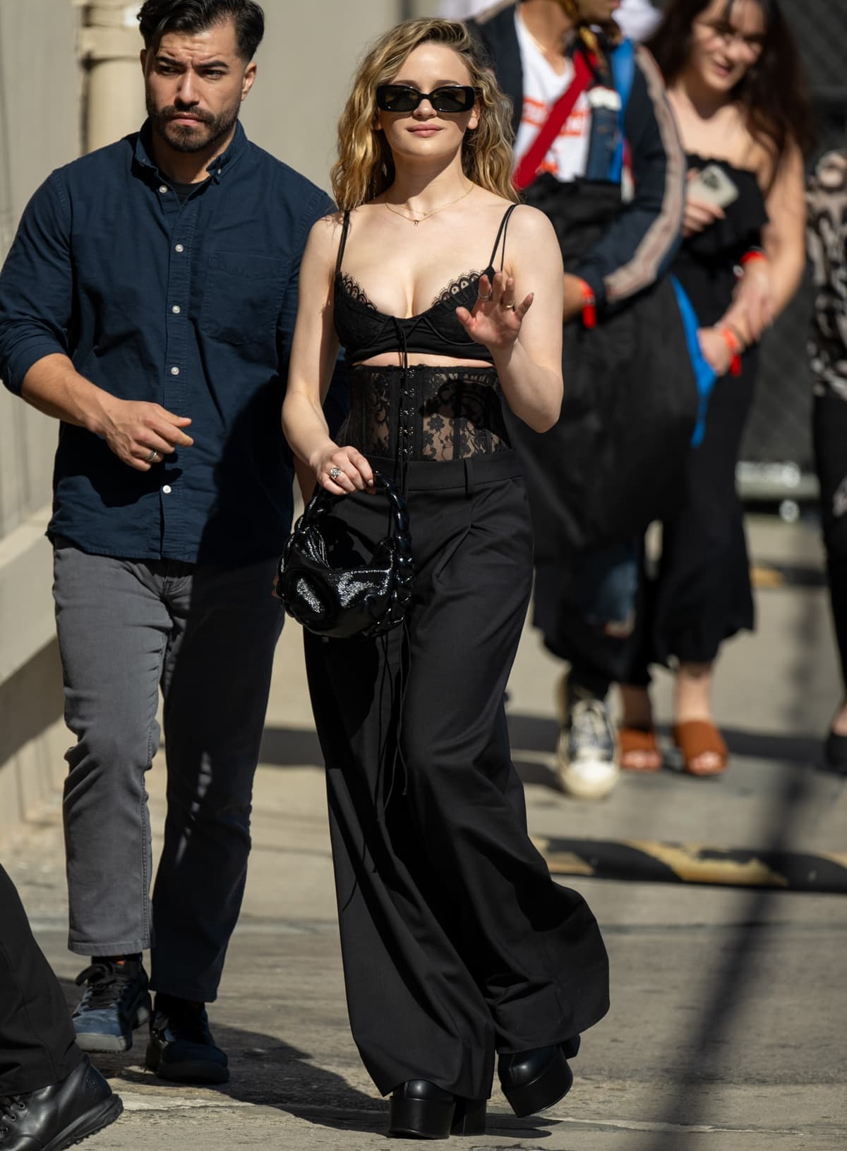 Arriving in style, Joey King turns heads at 'Jimmy Kimmel Live' wearing a bold Monse ensemble featuring a lace trim halter bralette and bustier pants, accessorized with Linda Farrow sunglasses, a Hereu bag, and striking Naked Wolfe platform boots