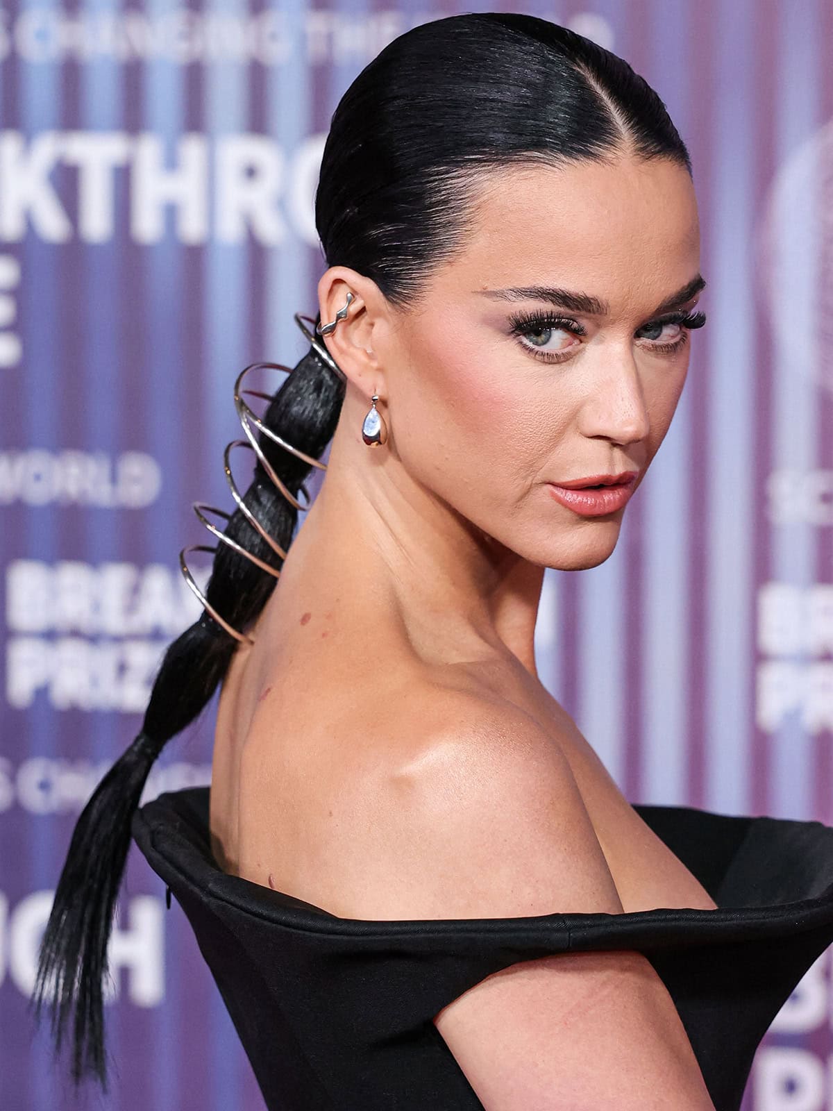 Katy Perry continues with the space-age theme of her ensemble by styling her sleek ponytail with silver ring hair jewelry by Kurumi and wearing silver earrings by Mara Paris