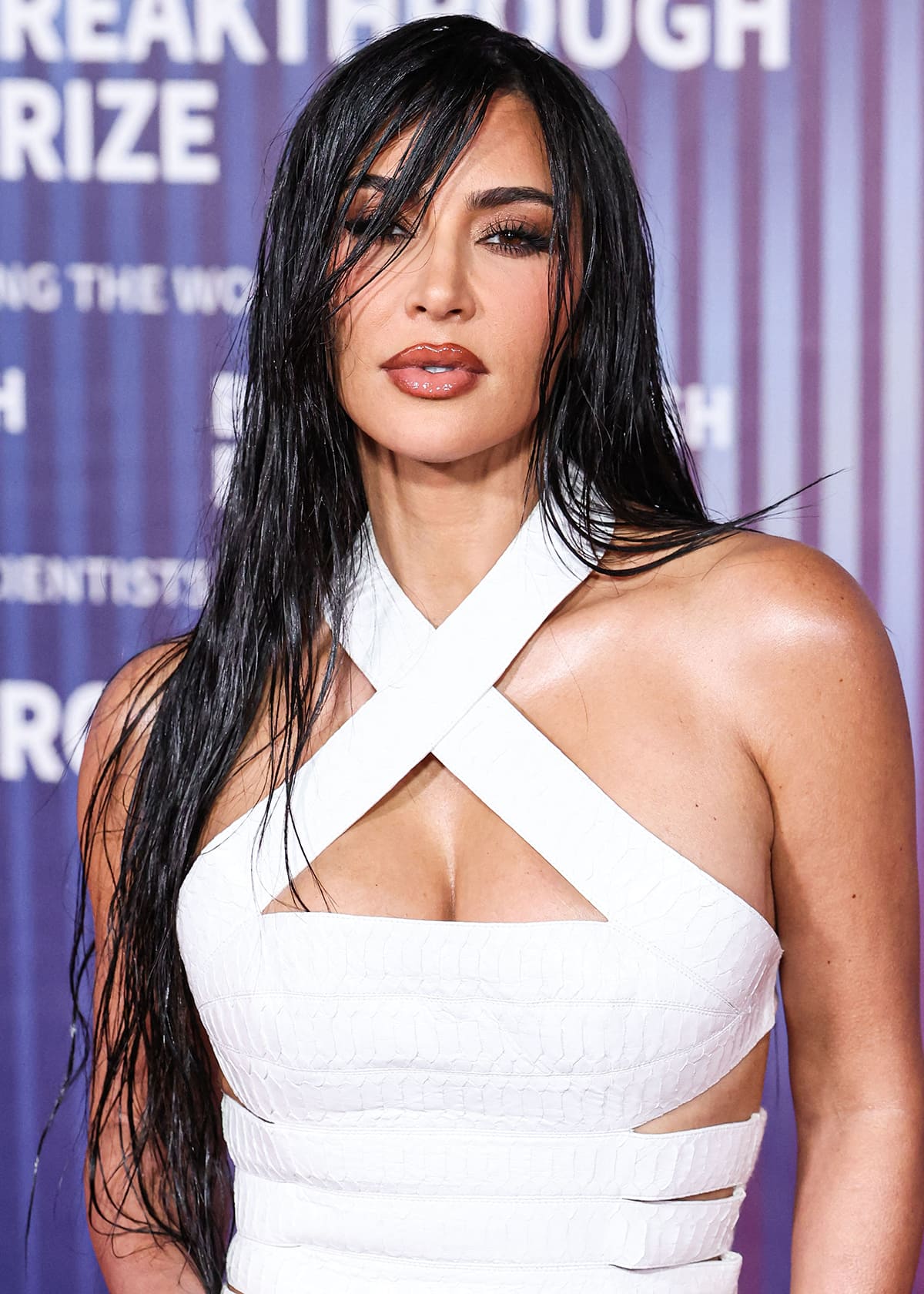 Kim Kardashian continues her look's sultry vibe by wearing a wet-look hairstyle and accentuating her striking features with bronze smokey eyeshadow and two-tone nude-brown lip gloss