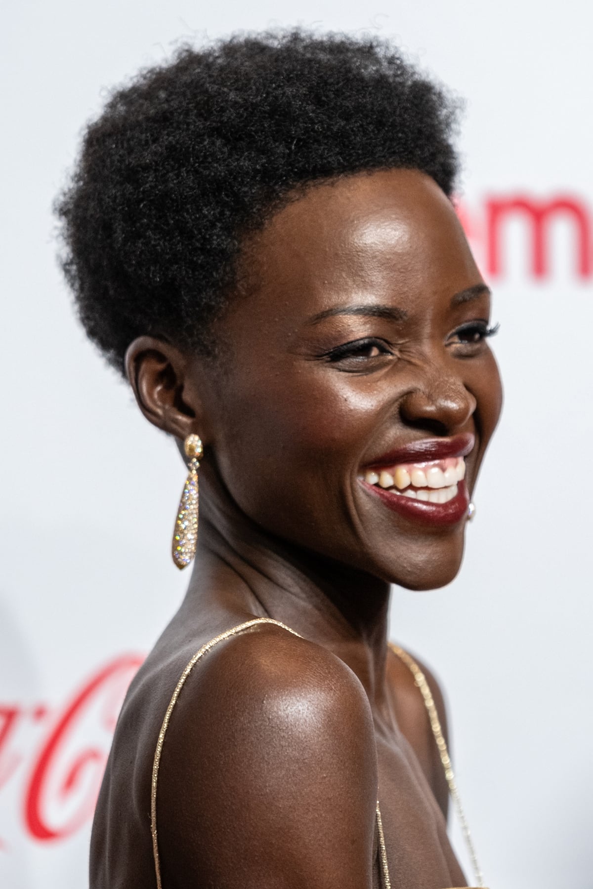 A close-up of Lupita Nyong'o's subtle yet striking makeup and gold jewelry, complementing her breathtaking gold ensemble perfectly