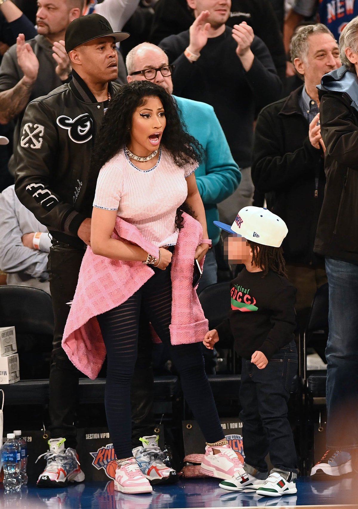Nicki Minaj looks comfy in a pink Chanel tee, black Alaia sheer striped leggings, and sneakers as she celebrates Easter Sunday with her husband, Kenneth Petty, and their son, Papa Bear, watching the New York Knicks game courtside