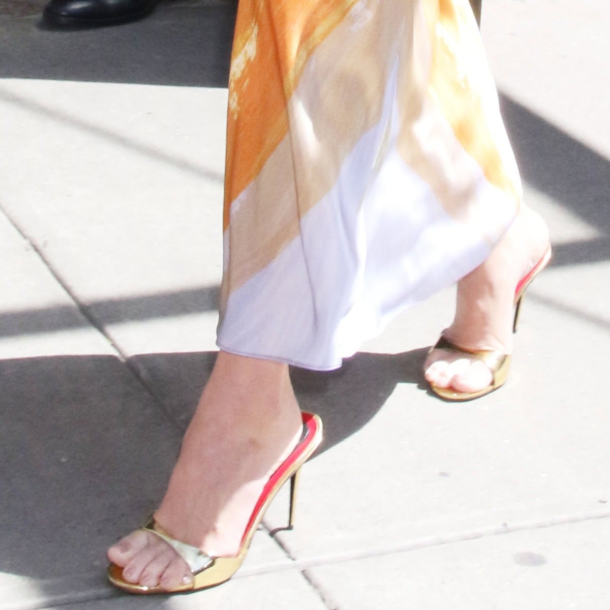 A closer look at Olivia Munn's golden Maison Ernest 'Lidylle' mules, pairing perfectly with her vibrant attire and adding a touch of glamour to her daytime look