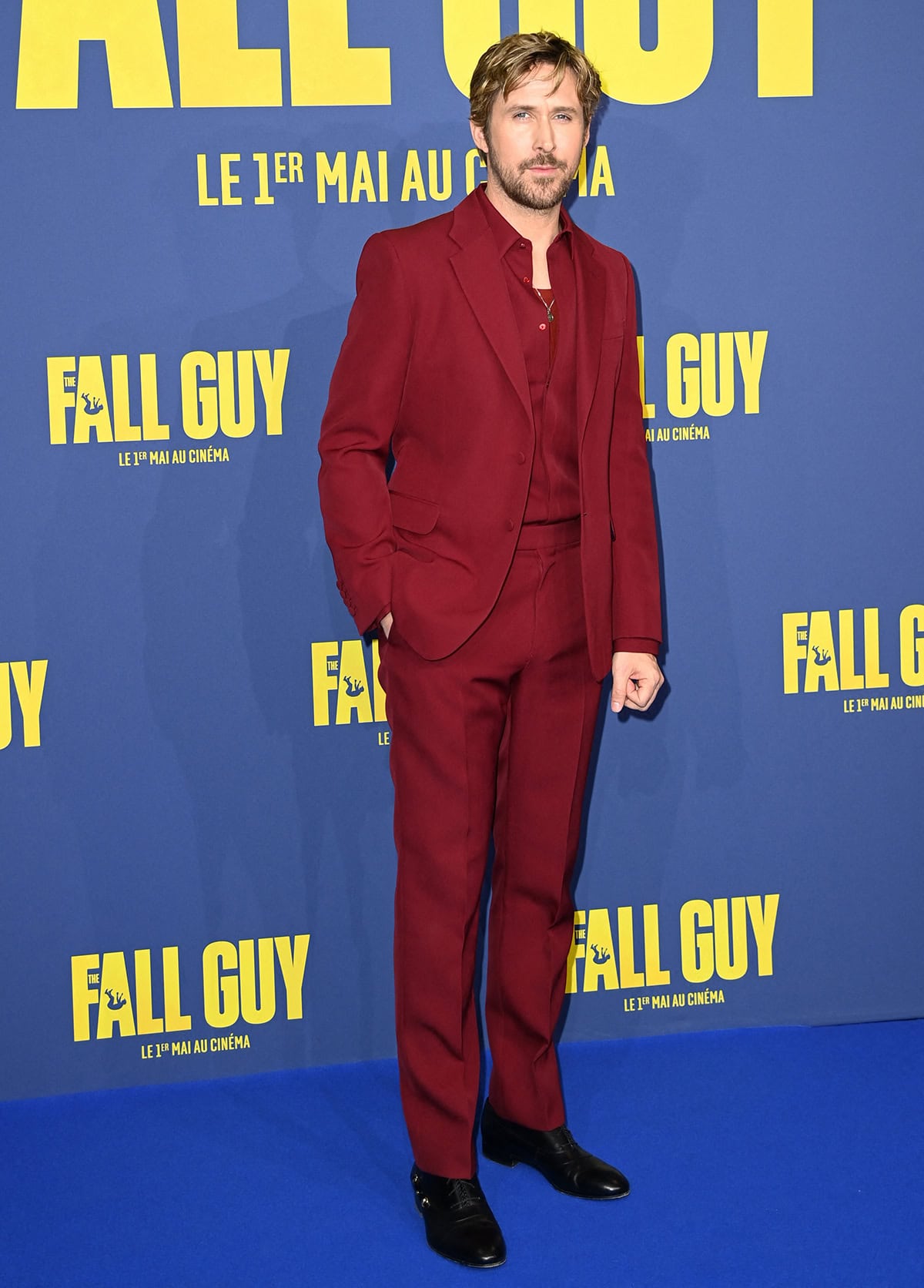 Ryan Gosling nails monochromatic dressing in a blood-red suit with a matching shirt and tee, finished with black Oxford shoes