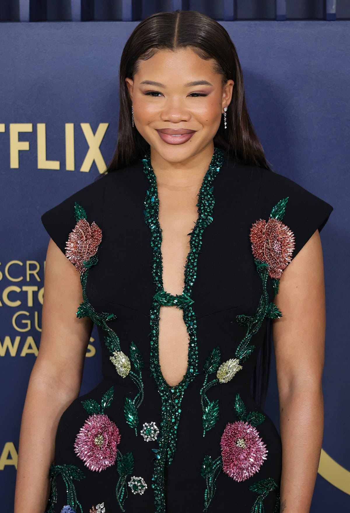 Storm Reid's hair was styled in a sleek middle part, cascading gracefully down her back, which complemented her bold makeup featuring dark smokey eyes and striking mauve lips