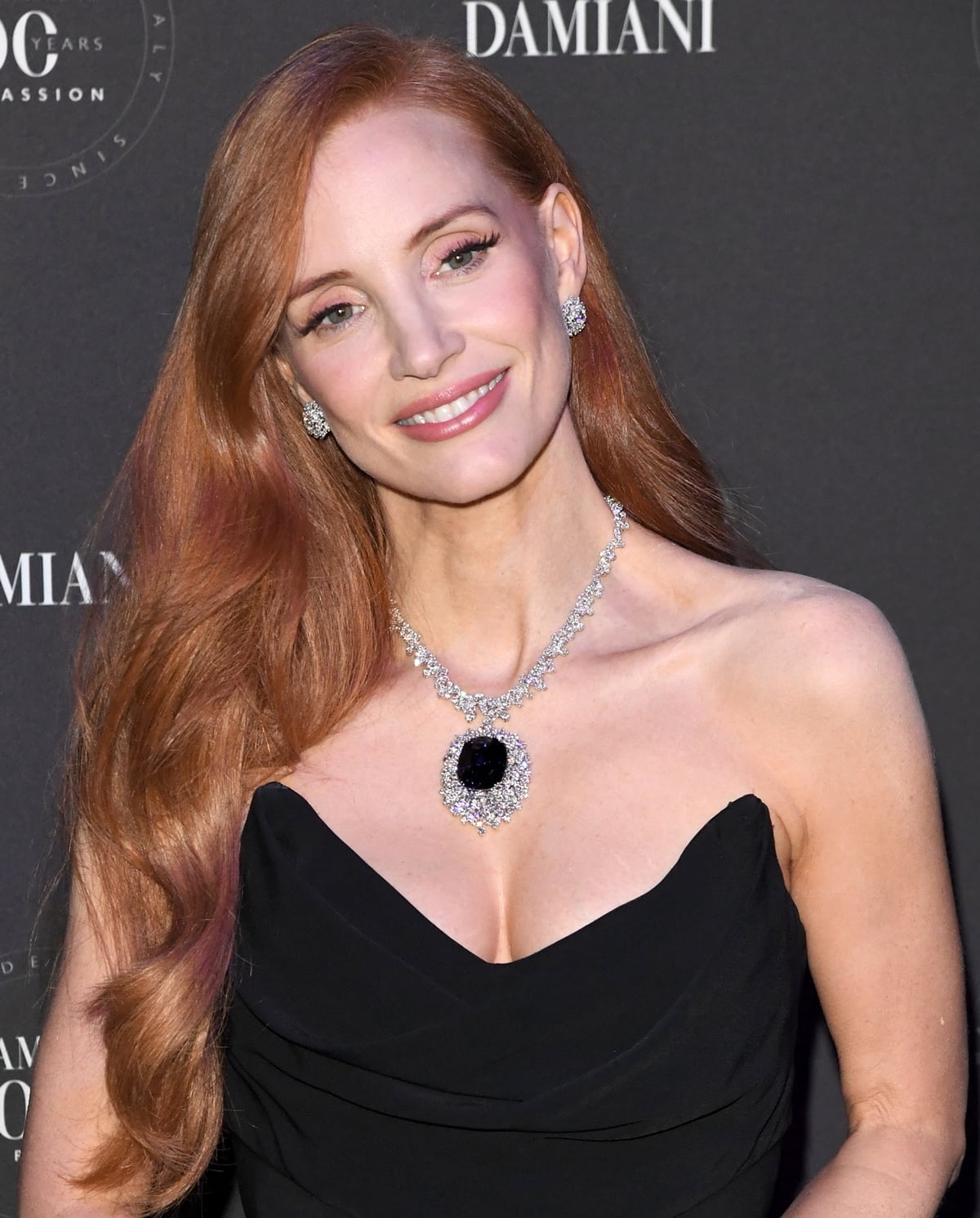 The Mismosa Eternal Blue necklace, featured on Jessica Chastain, is a masterpiece from Damiani's 100th-anniversary collection, showcasing 100.19 carats of dazzling diamonds encircling a stunning large sapphire, embodying Italian craftsmanship and luxury