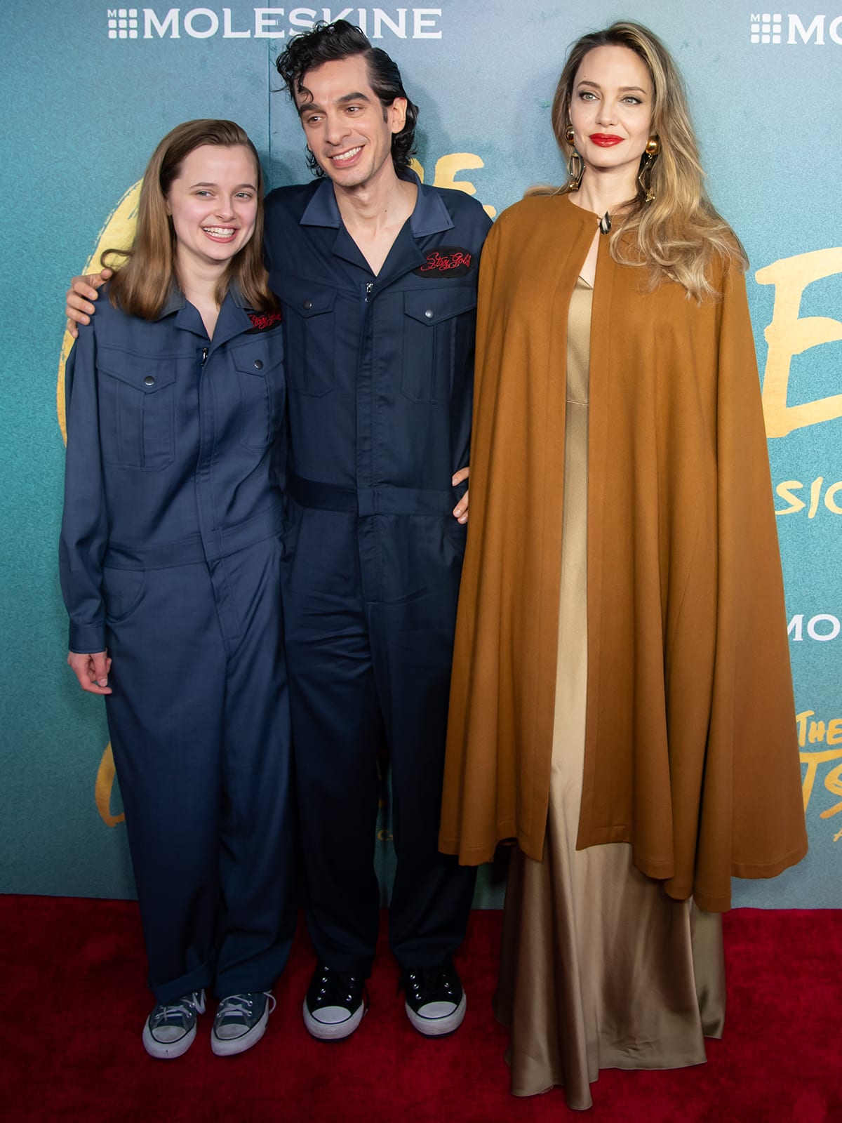 Vivienne Jolie-Pitt matches with composer-writer Justin Levine in a navy blue jumpsuit as a reference to the musical, while Angelina Jolie keeps a majestic look in a gold gown