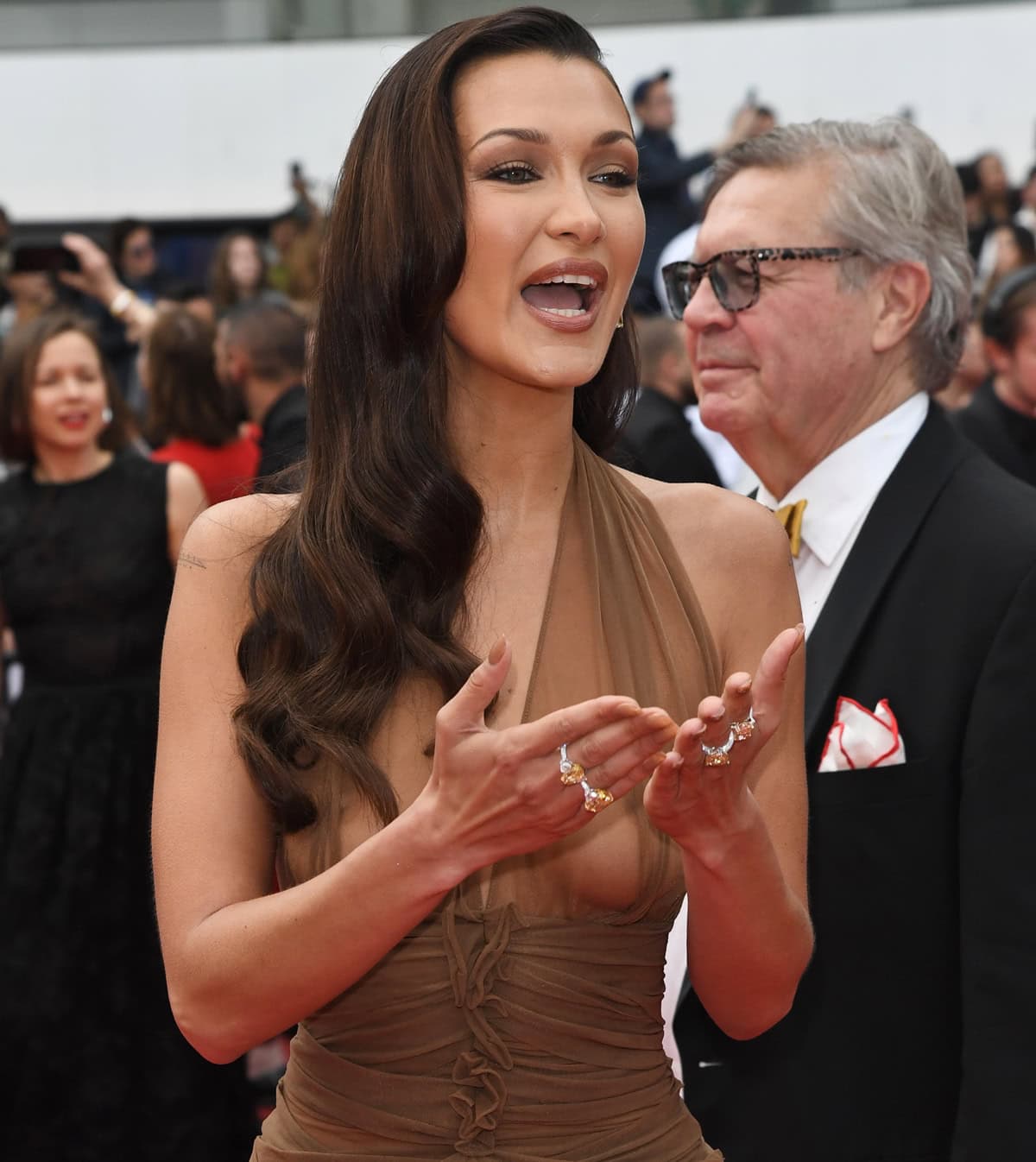 Bella Hadid's glamorous makeup and Old Hollywood waves perfectly complement her ensemble, adding a classic touch to her modern look