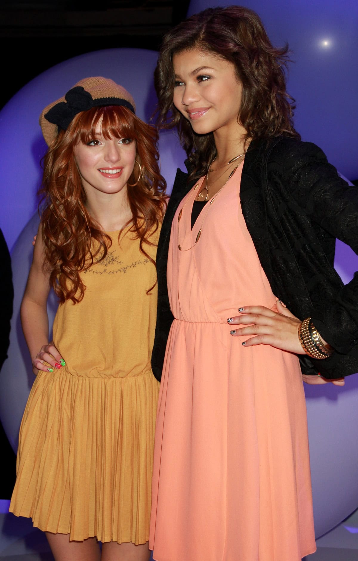 Bella Thorne and Zendaya showcase a charming height contrast with Bella's petite frame complemented by Zendaya's taller stature, both styled in vibrant, youthful dresses