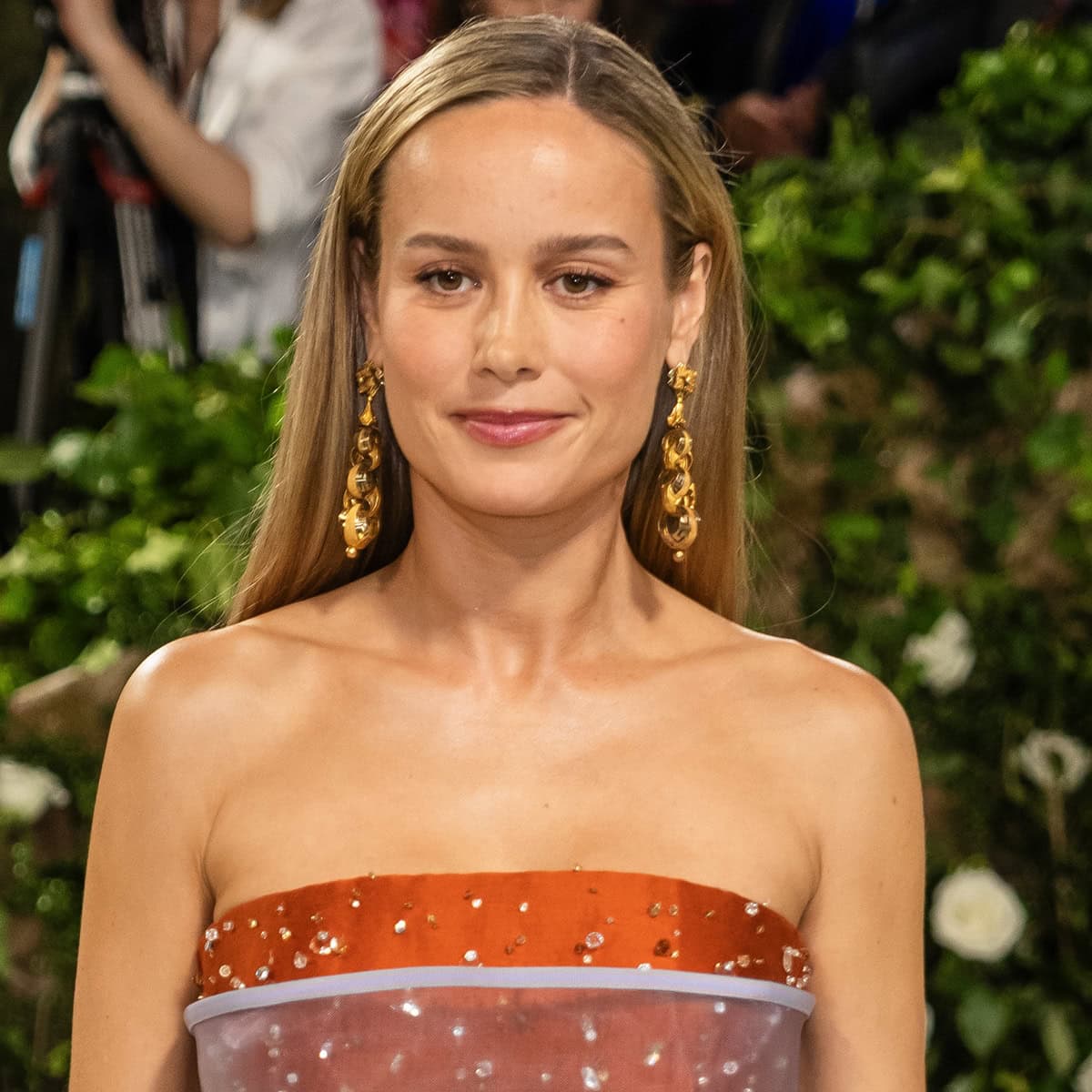 Brie Larson complements her Met Gala ensemble with Fred Leighton Georgian 18K yellow gold Greek key motif pendant earrings, featuring interlocking links and textured rings that add a touch of timeless sophistication