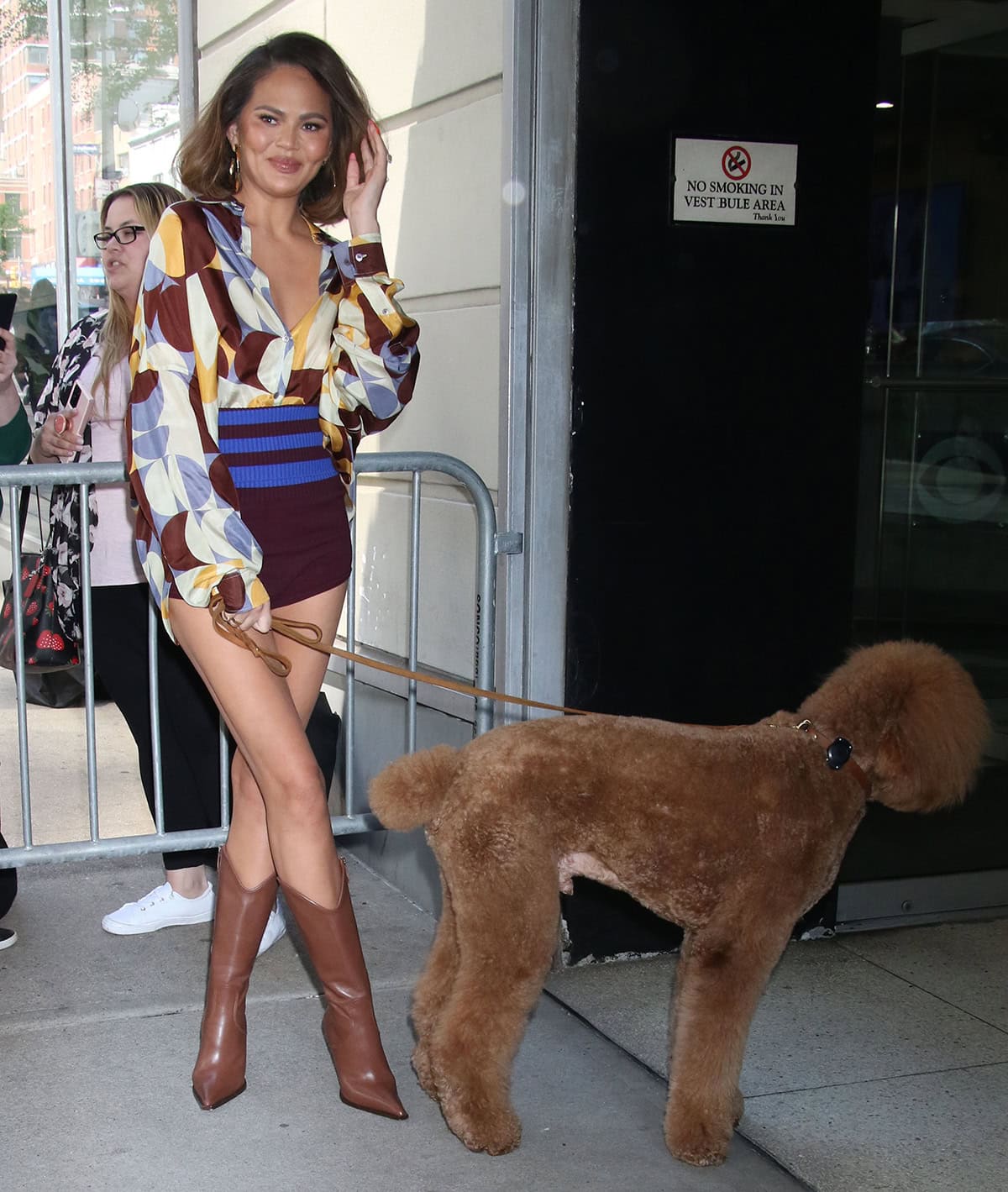 Chrissy Teigen parades her long legs in brown knitted striped briefs and a geometric-printed silk shirt by Dries Van Noten