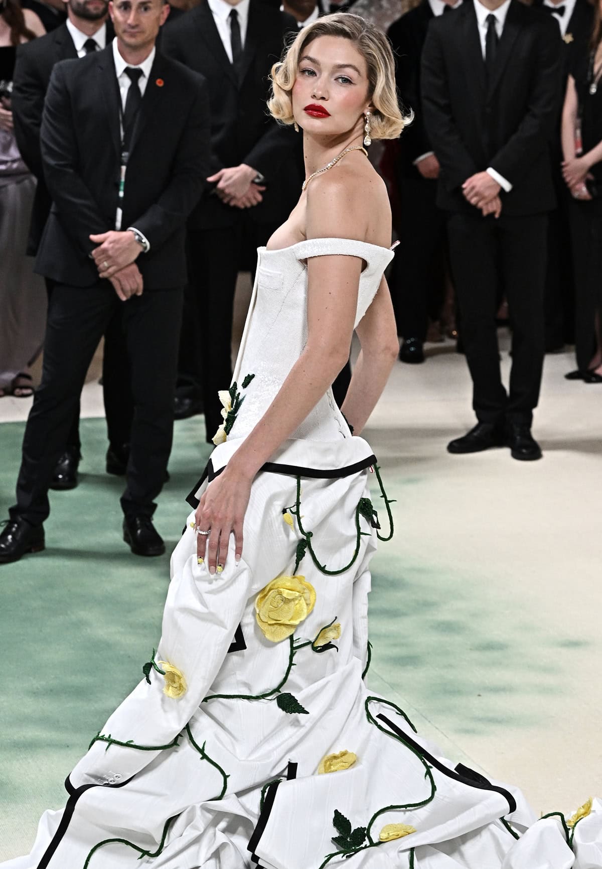 Gigi Hadid makes a grand statement at the Met Gala, from her garden-inspired gown to her delicate, vintage-inspired hair and bold red lips