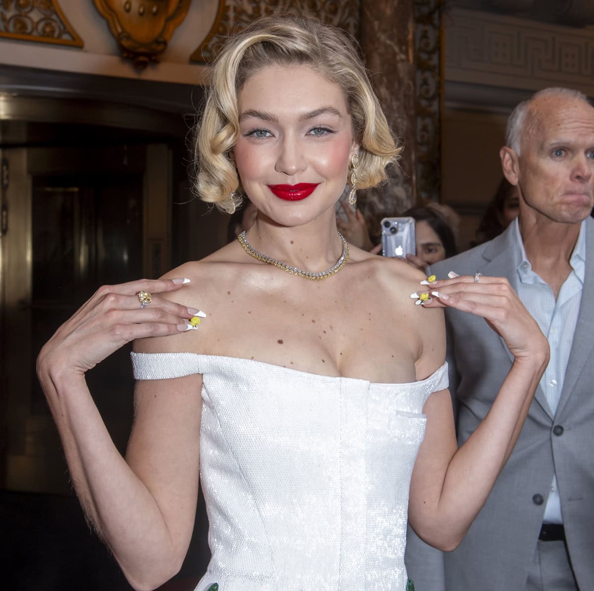 Gigi Hadid sparkles at the Met Gala with a touch of classic glamour: a bold red lip, a precision-cut bob, and a manicure that mirrors the garden theme, complemented by Chopard's exquisite diamond jewelry