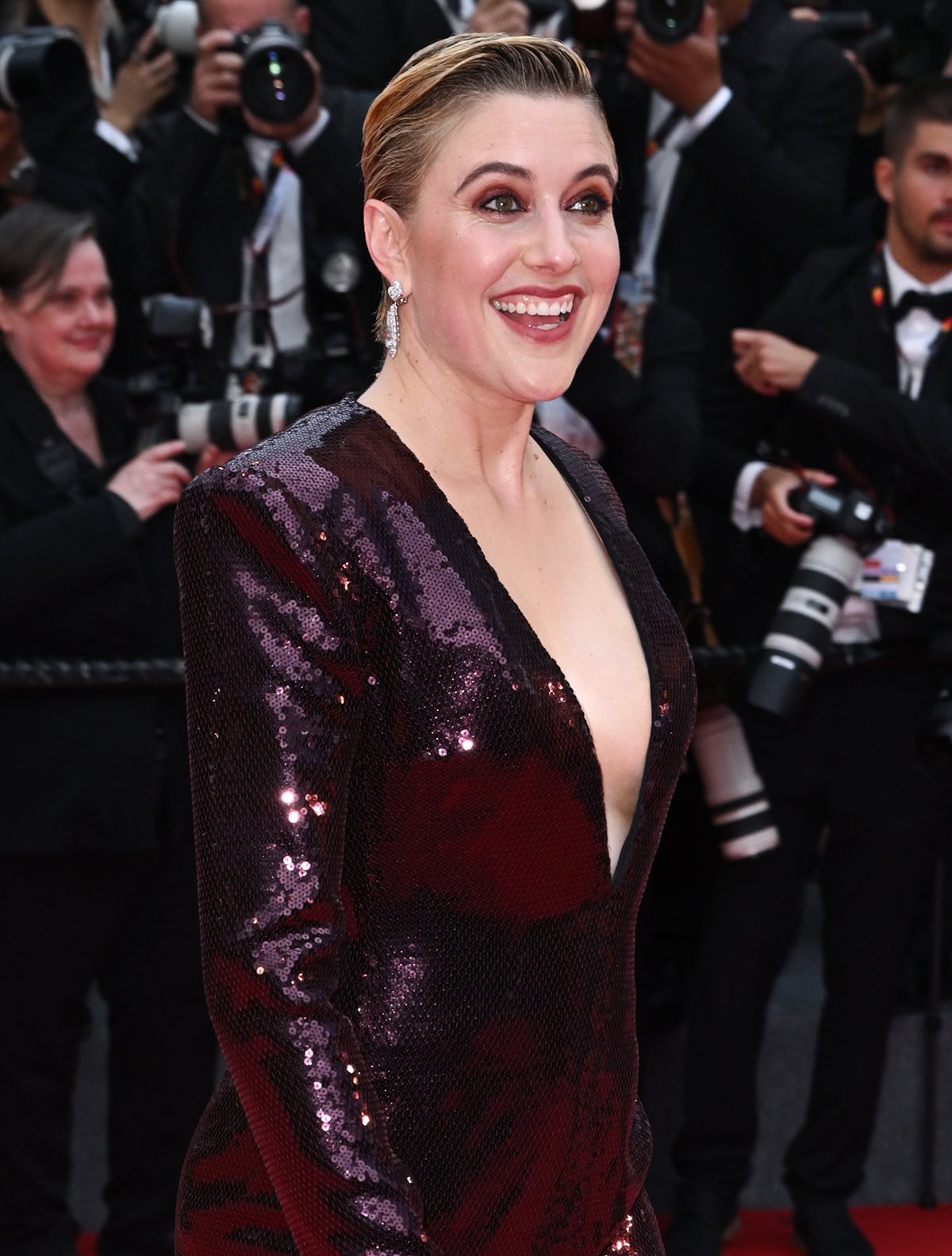 Greta Gerwig finishes off her sleek, dramatic look with smokey vampy eyeshadow, rosy blush, and complementary lipstick