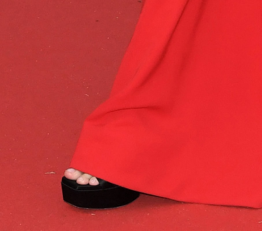 Greta Gerwig teams the red gown with black open-toe sandals, showcasing her toes