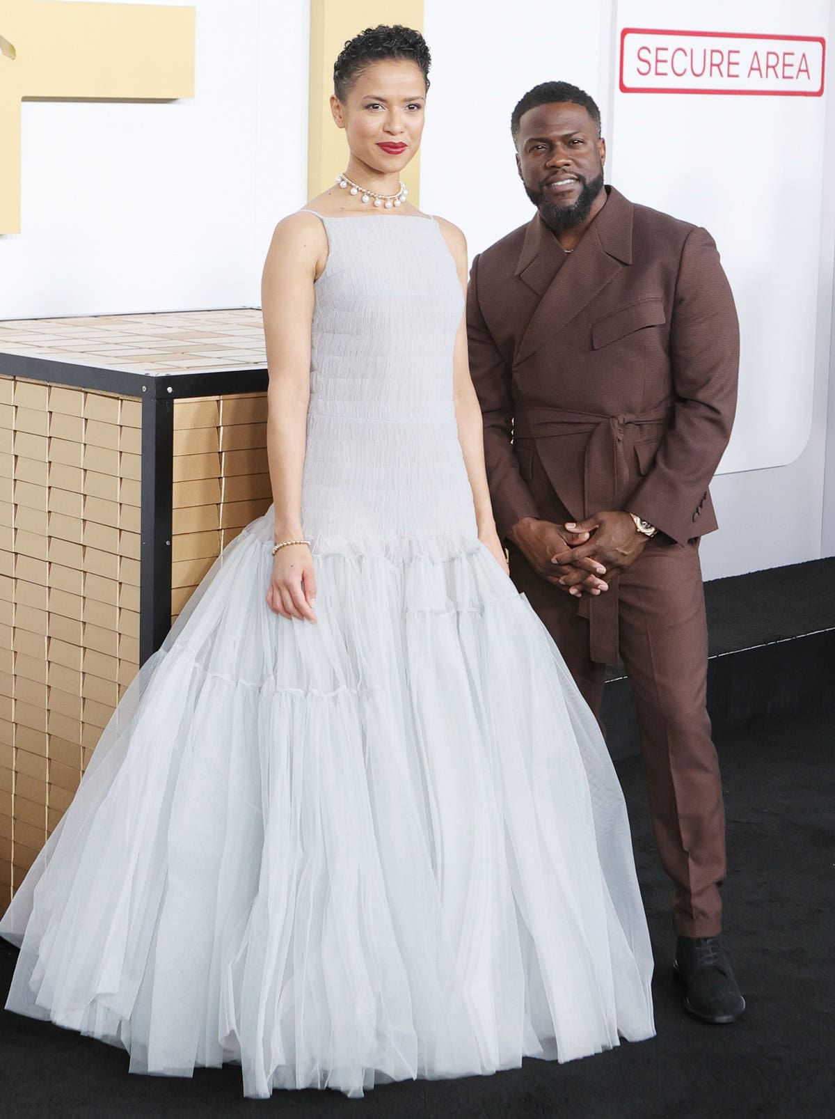 At the Lift premiere in New York, Gugu Mbatha-Raw looked significantly taller than Kevin Hart, pairing hidden high heels with a voluminous Molly Goddard gown, while Kevin wore a sharp brown double-breasted suit