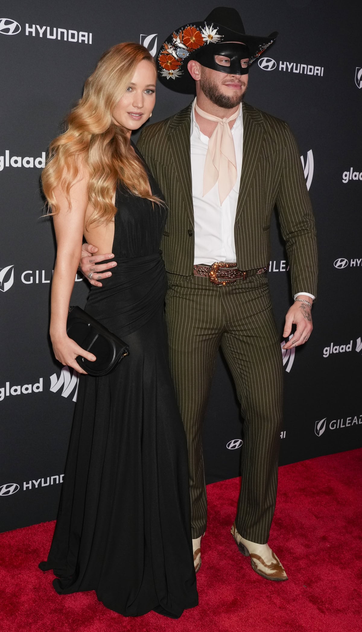 Jennifer Lawrence poses elegantly in a black Alaïa gown alongside Orville Peck, who sports a distinctive masked look, at the 35th Annual GLAAD Media Awards