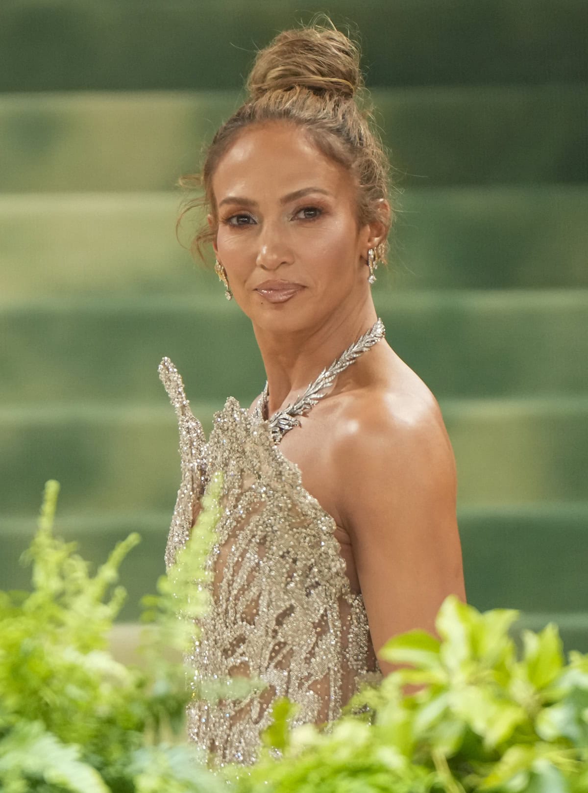 Jennifer Lopez completes her butterfly-themed look with butterfly-inspired glam, wearing a textured top knot and bronzed makeup