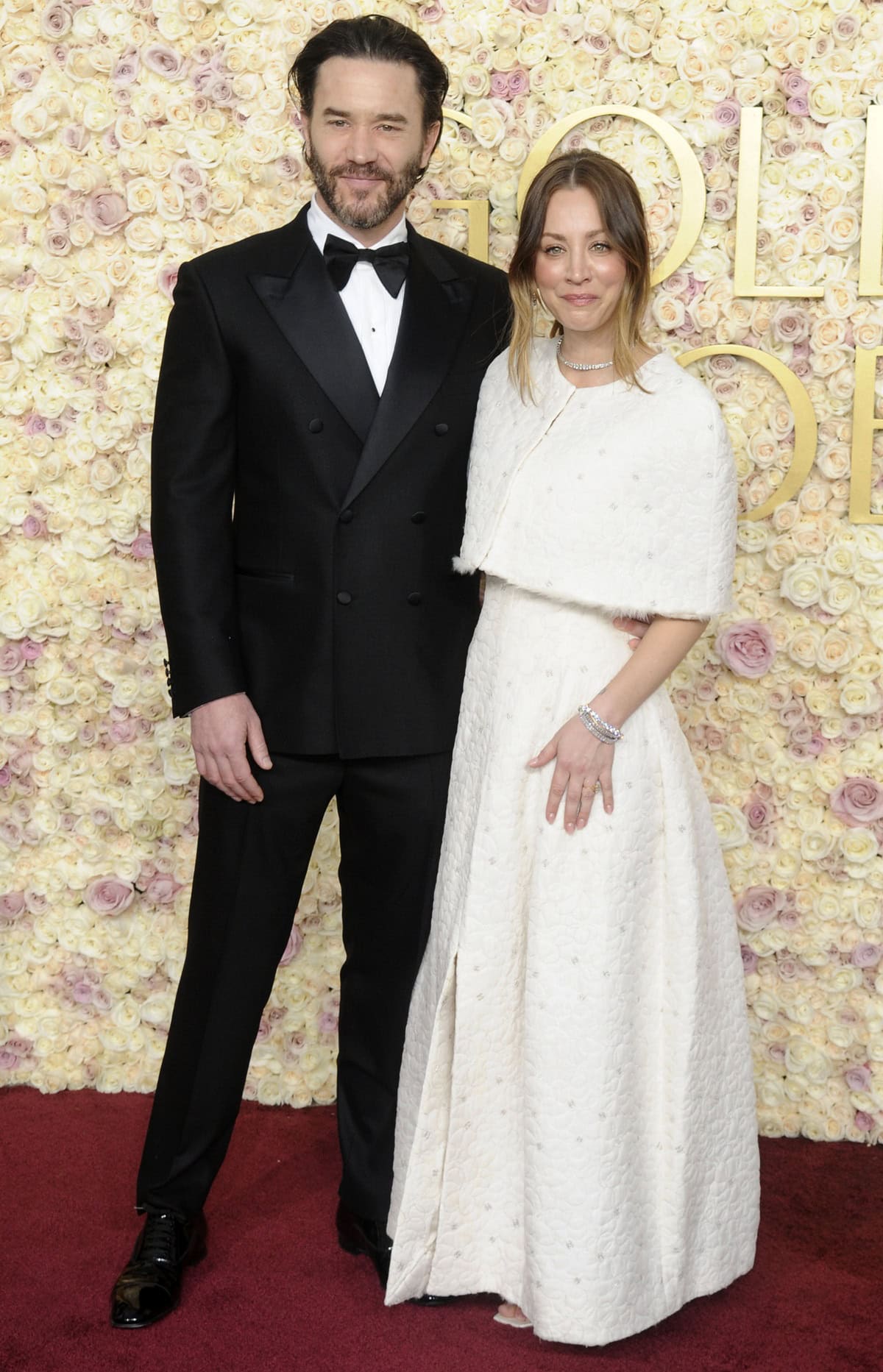 Kaley Cuoco, joined by fiancé Tom Pelphrey, wore a vintage-inspired ivory Chanel Fall 2001 A-line dress paired with barely visible Jimmy Choo Skye crystal-embellished satin sandals at the 2025 Golden Globe Awards in Beverly Hills