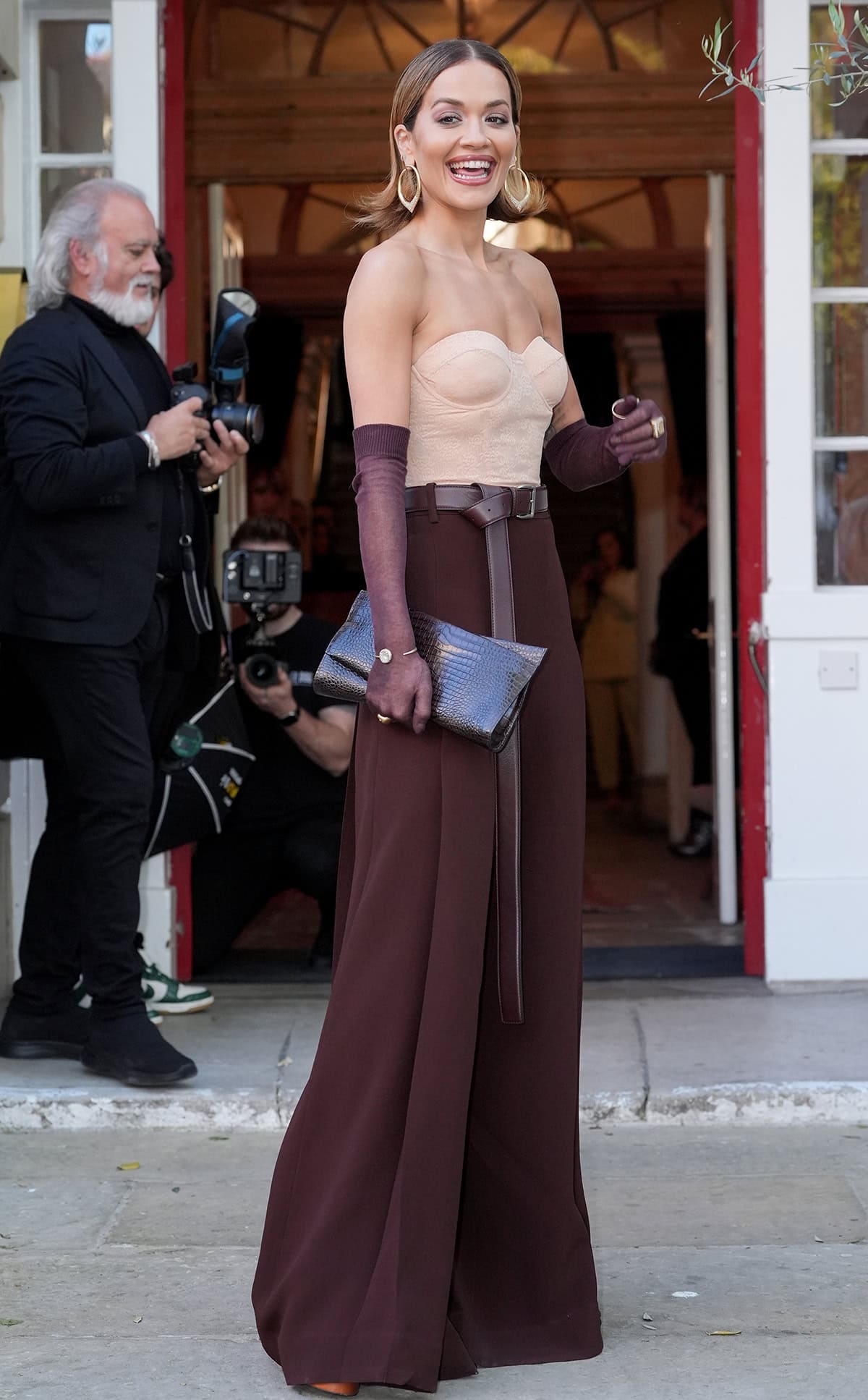 Rita Ora turns heads in a strapless nude corset top tucked into a pair of belted chocolate brown wide-leg pants