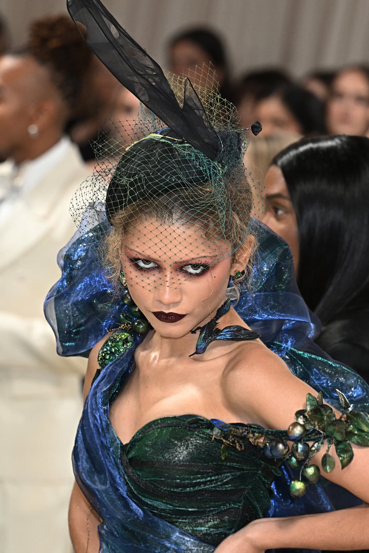 Zendaya is seen sporting a Stephen Jones "reverse swatching" beret hat made of silver metal wire with a black hand-painted plume-like voile sitting atop a hand-painted net veil