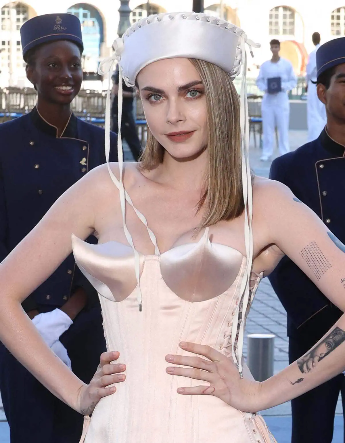 Cara Delevingne styles her already whimsical pale pink mini-dress with a white silk sailor hat with whipstitch trims and lace-up ribbons