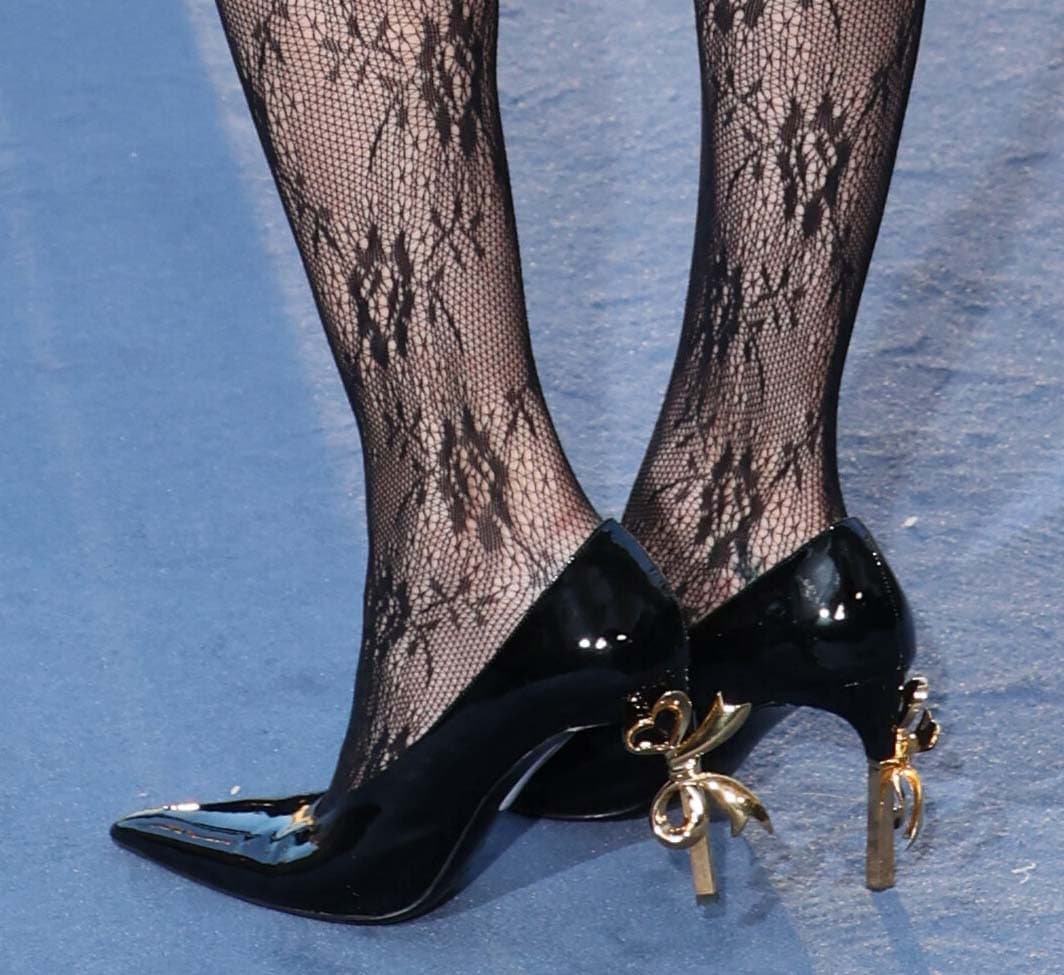 Diane Kruger updates the 1920s femme-fatale style with modern femininity by wearing black patent pointed-toe shoes with gold-tone heels and a sculptural bow accent