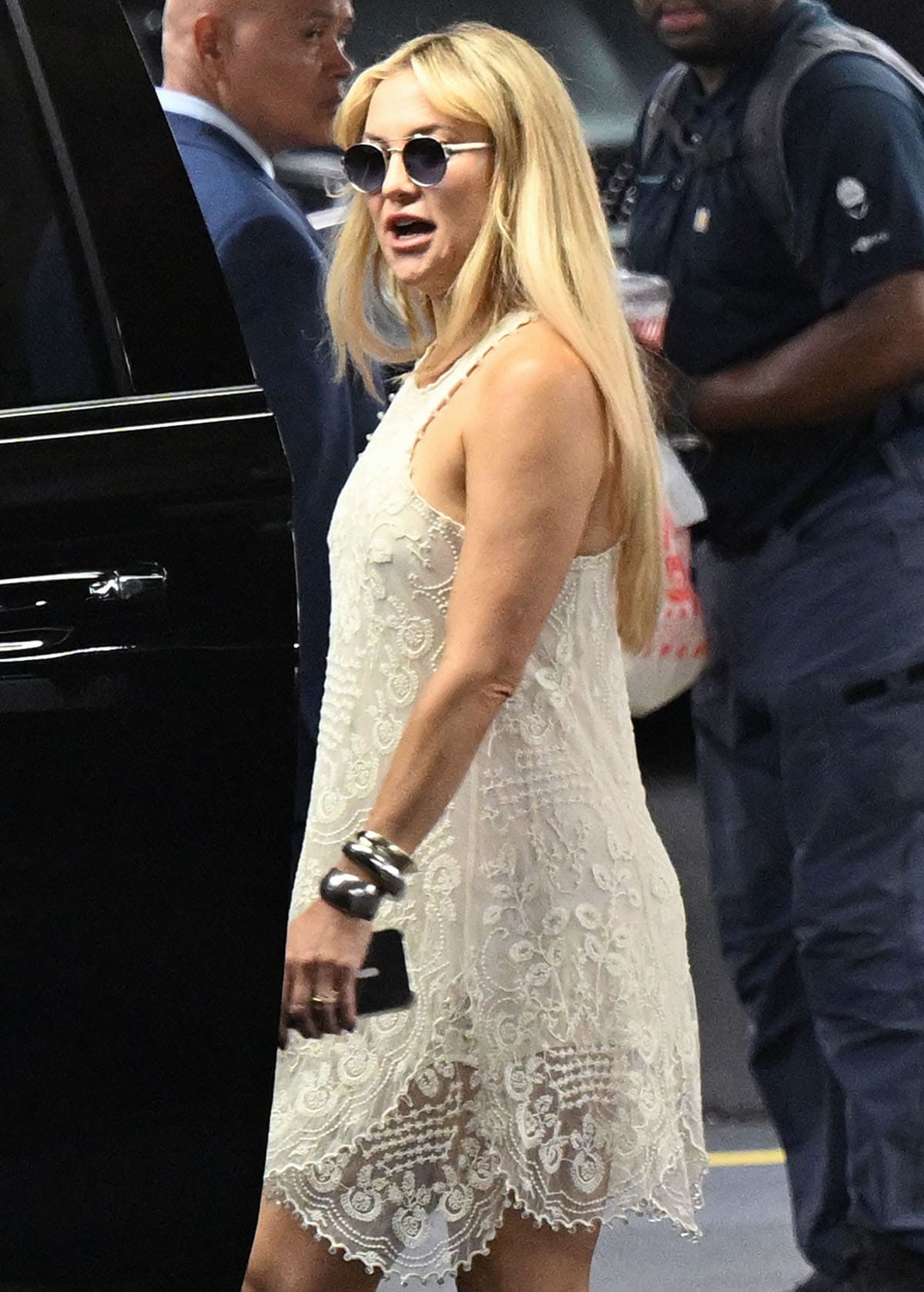 Kate Hudson enhances her dress's bohemian vibe by accessorizing with silver bangles and round sunglasses